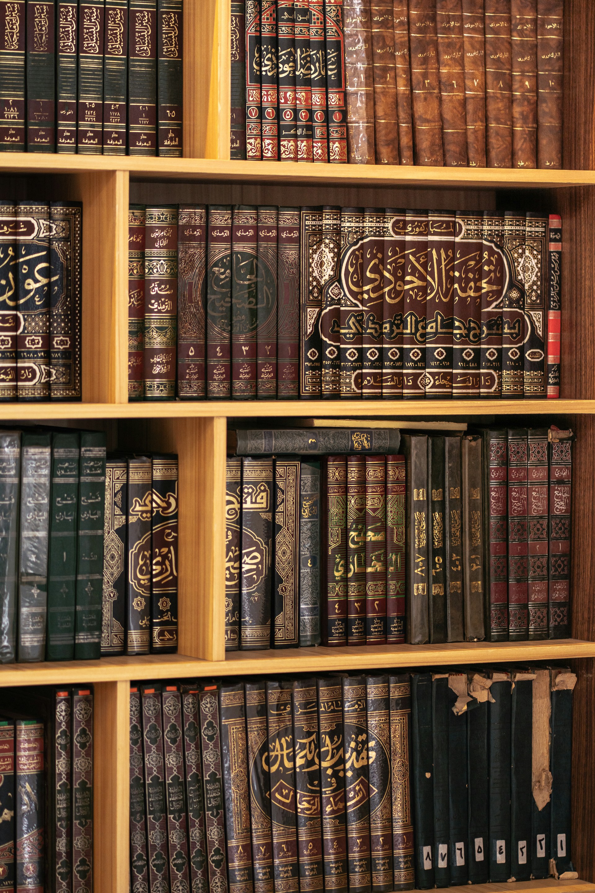 Bookshelf filled with beautifully bound, aged books.