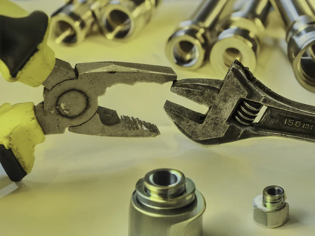 Pliers and a wrench gripping metal pipe parts