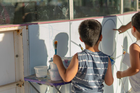 Children are painting a mural on the wall.