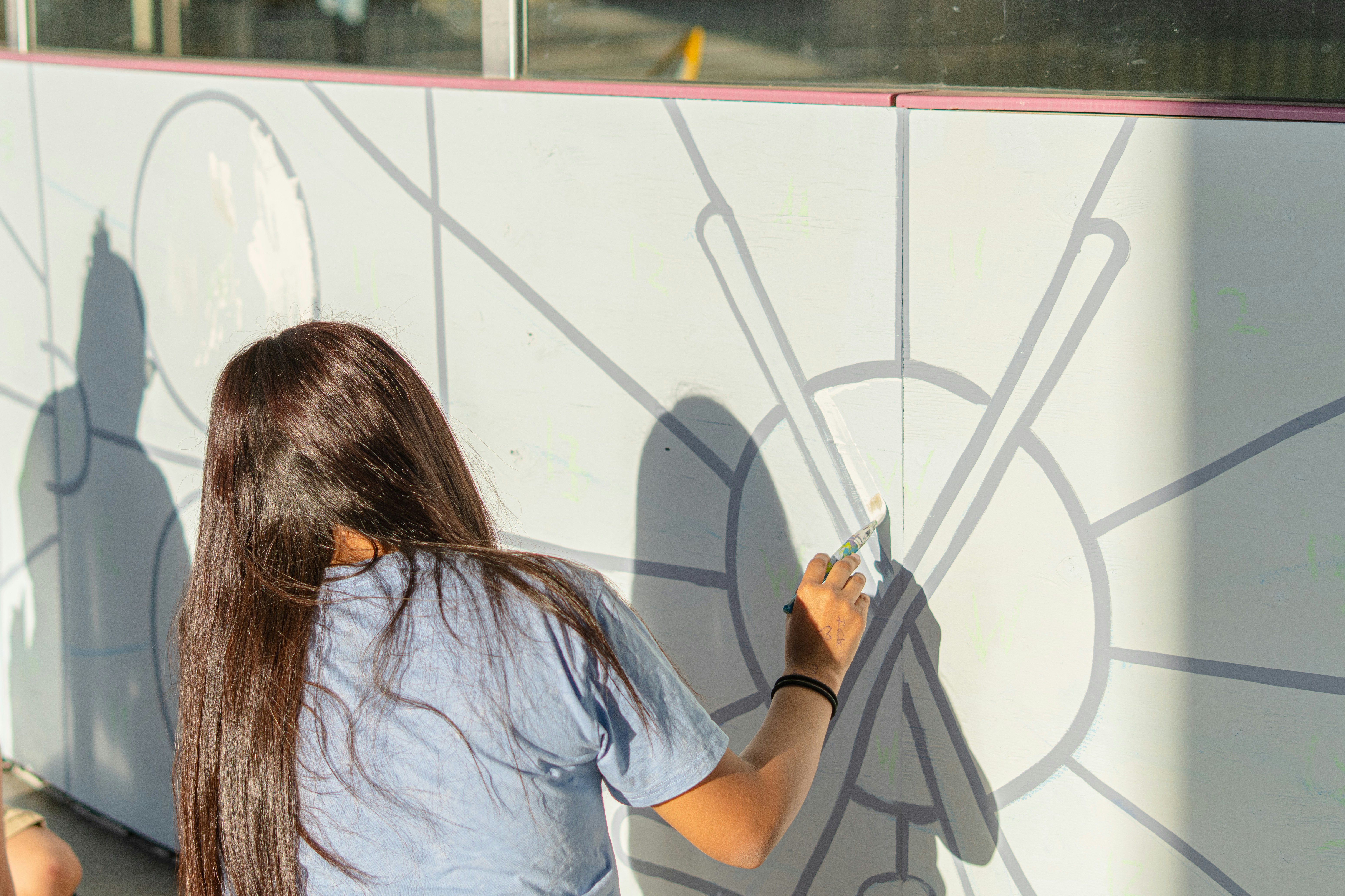 A woman paints a mural on a wall.
