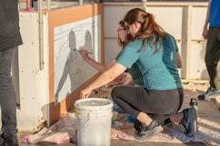 Two people are painting on a wall.