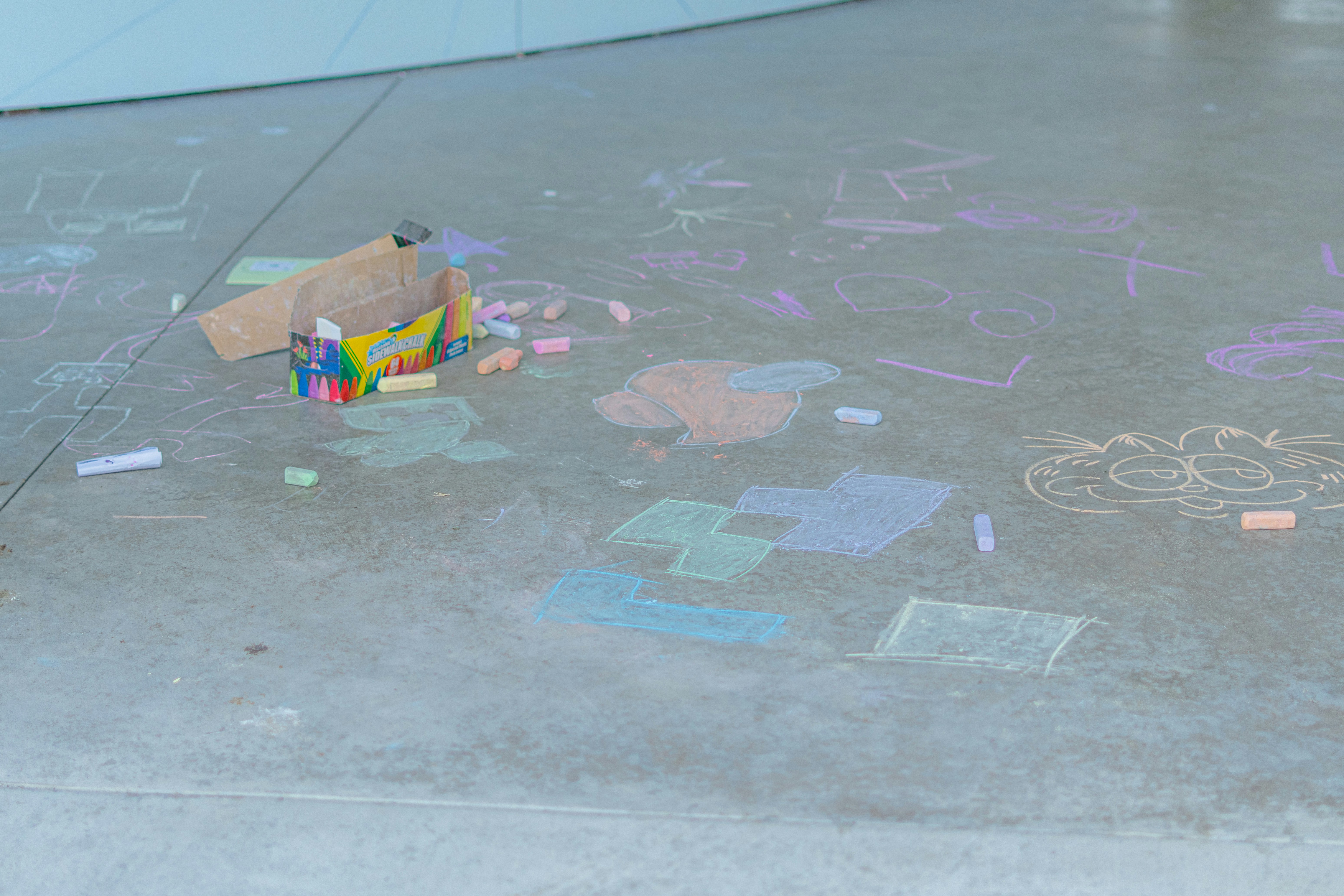 Chalk drawings and scattered materials on concrete.