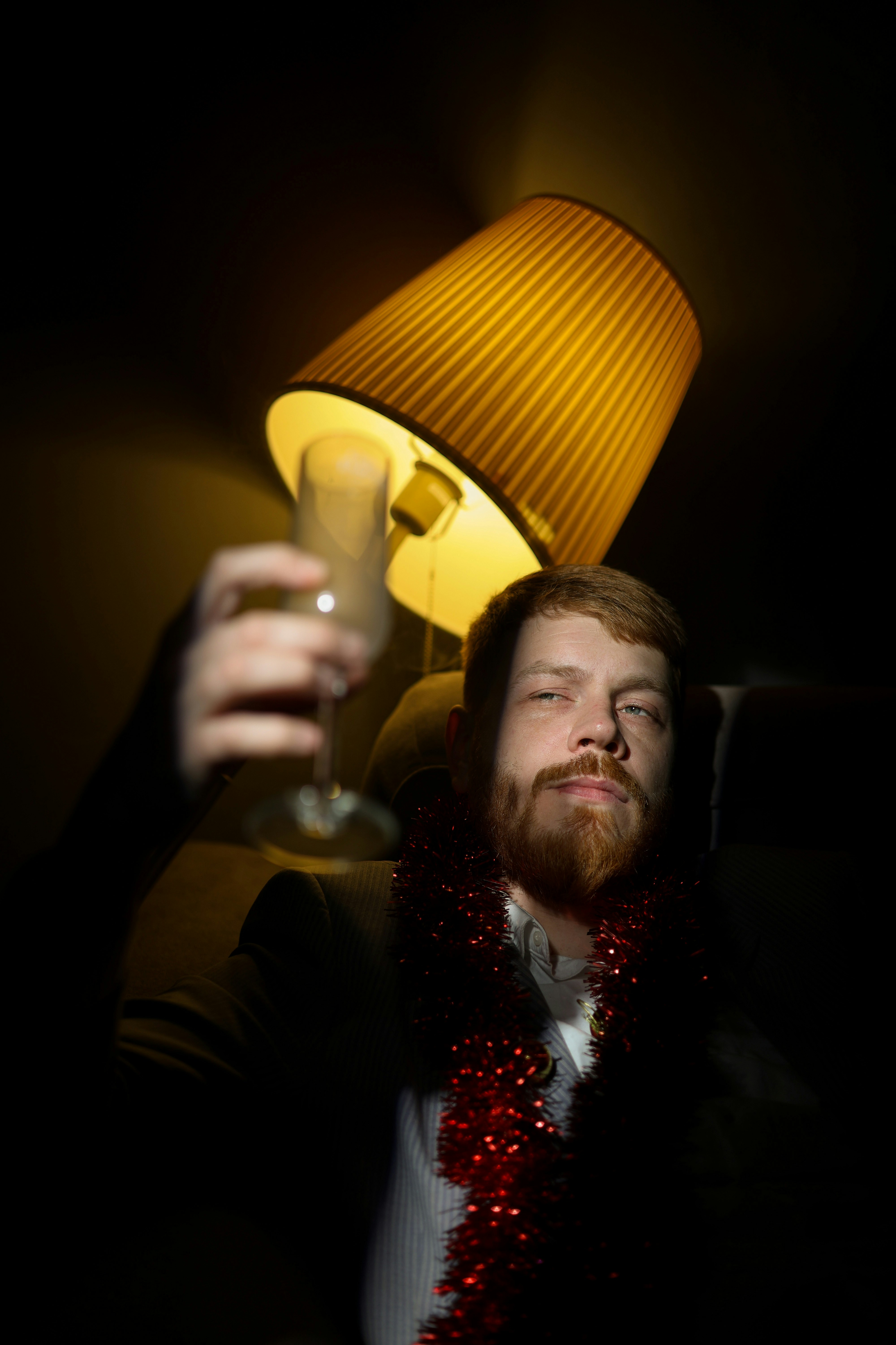 Man cheers with champagne under a dim lamp.