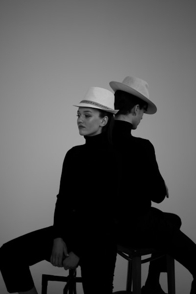 Two people, back to back, wearing hats.