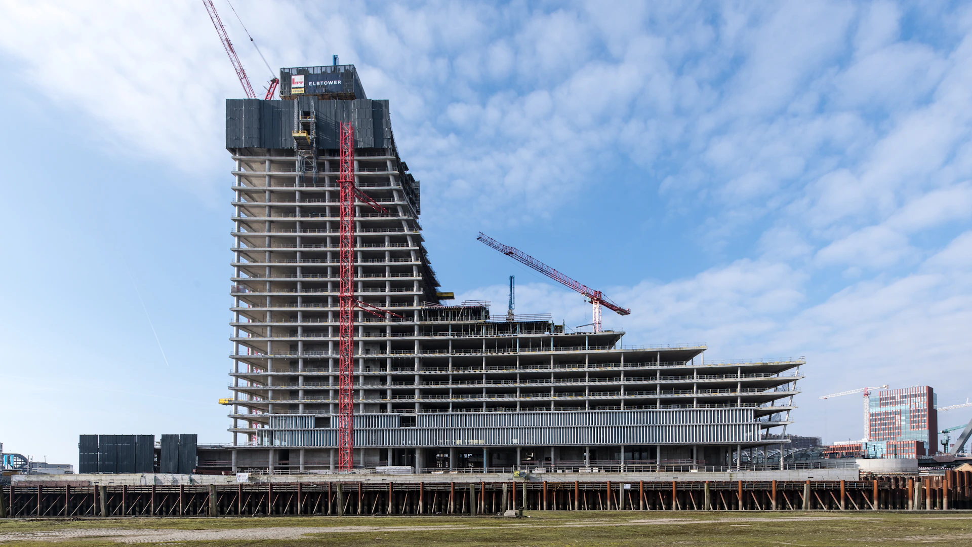 A skyscraper is under construction near water.
