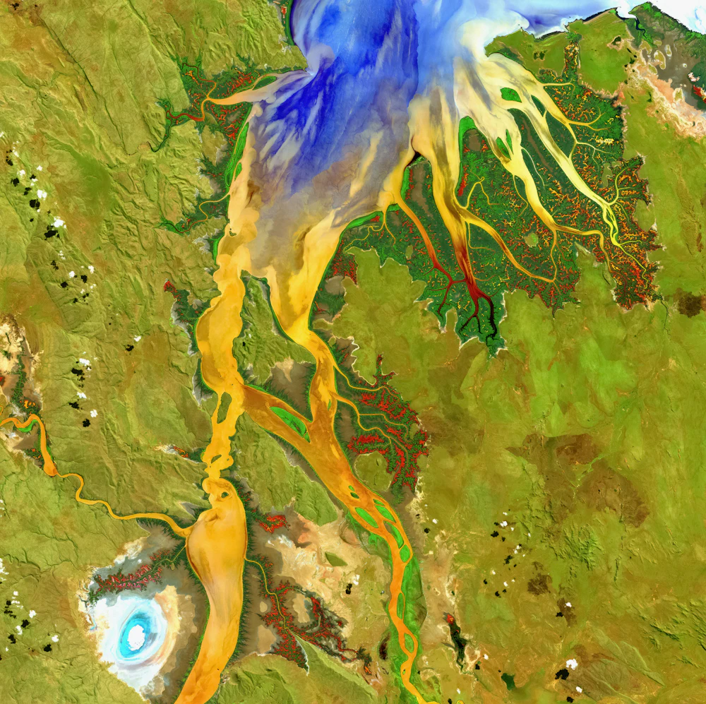Satellite view of a river delta with colourful sediment