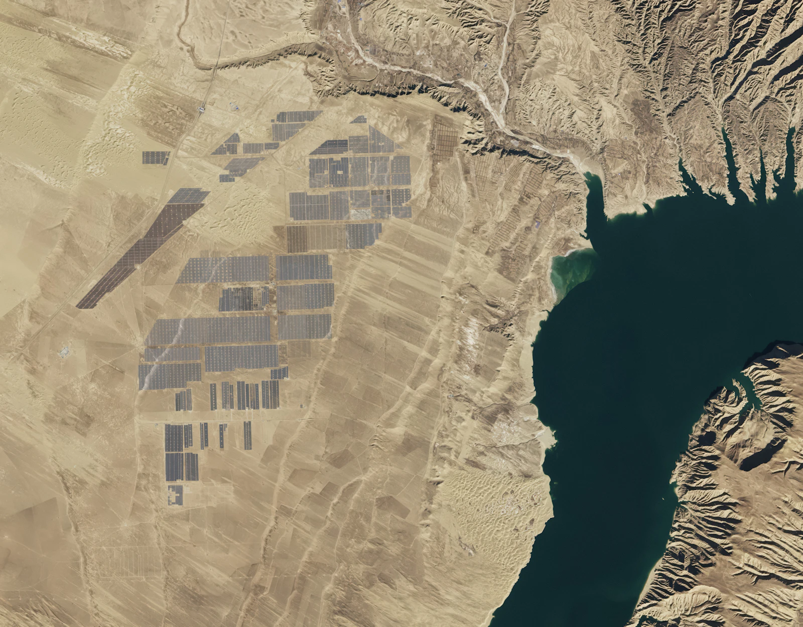 Satellite view of a large solar farm next to a reservoir