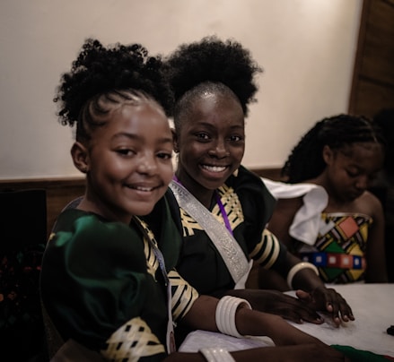 Three smiling girls are dressed in cultural attire.
