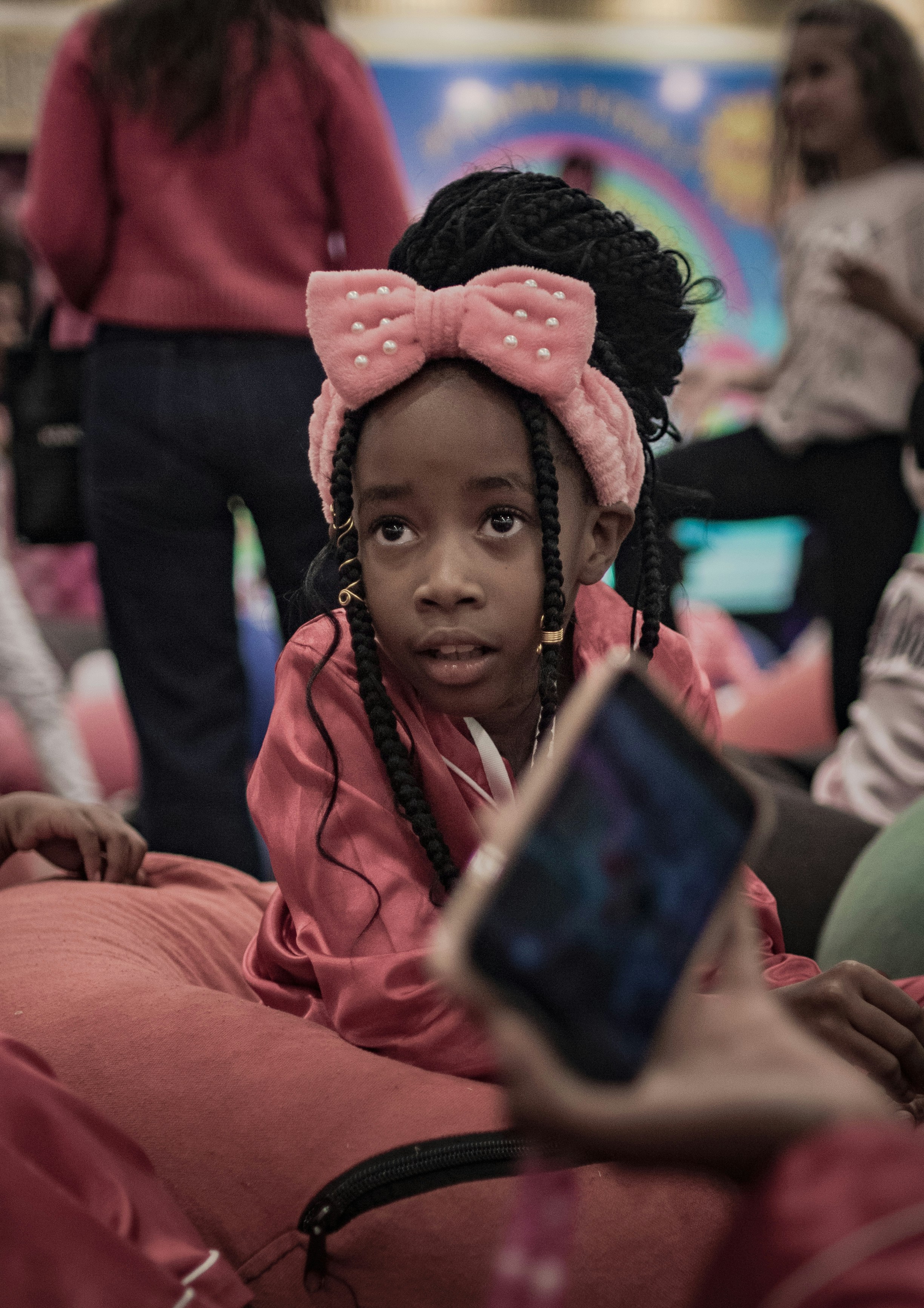 Brown skin girl holding a kazoo while watching the teacher on his laptop