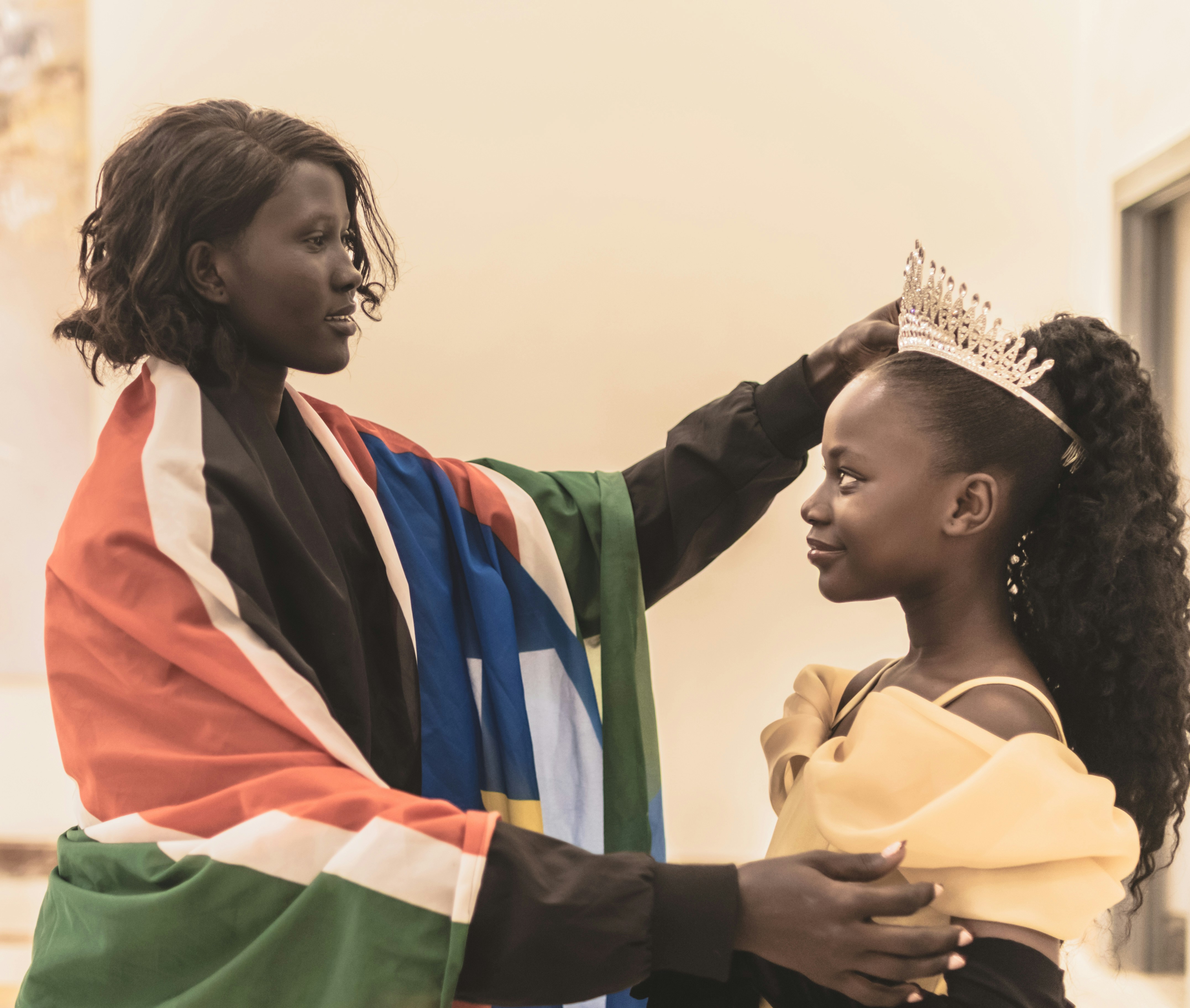 South Sudanese woman adjusts the crown of a beauty pageant contestant