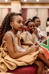 Young girls in elegant attire are seated
