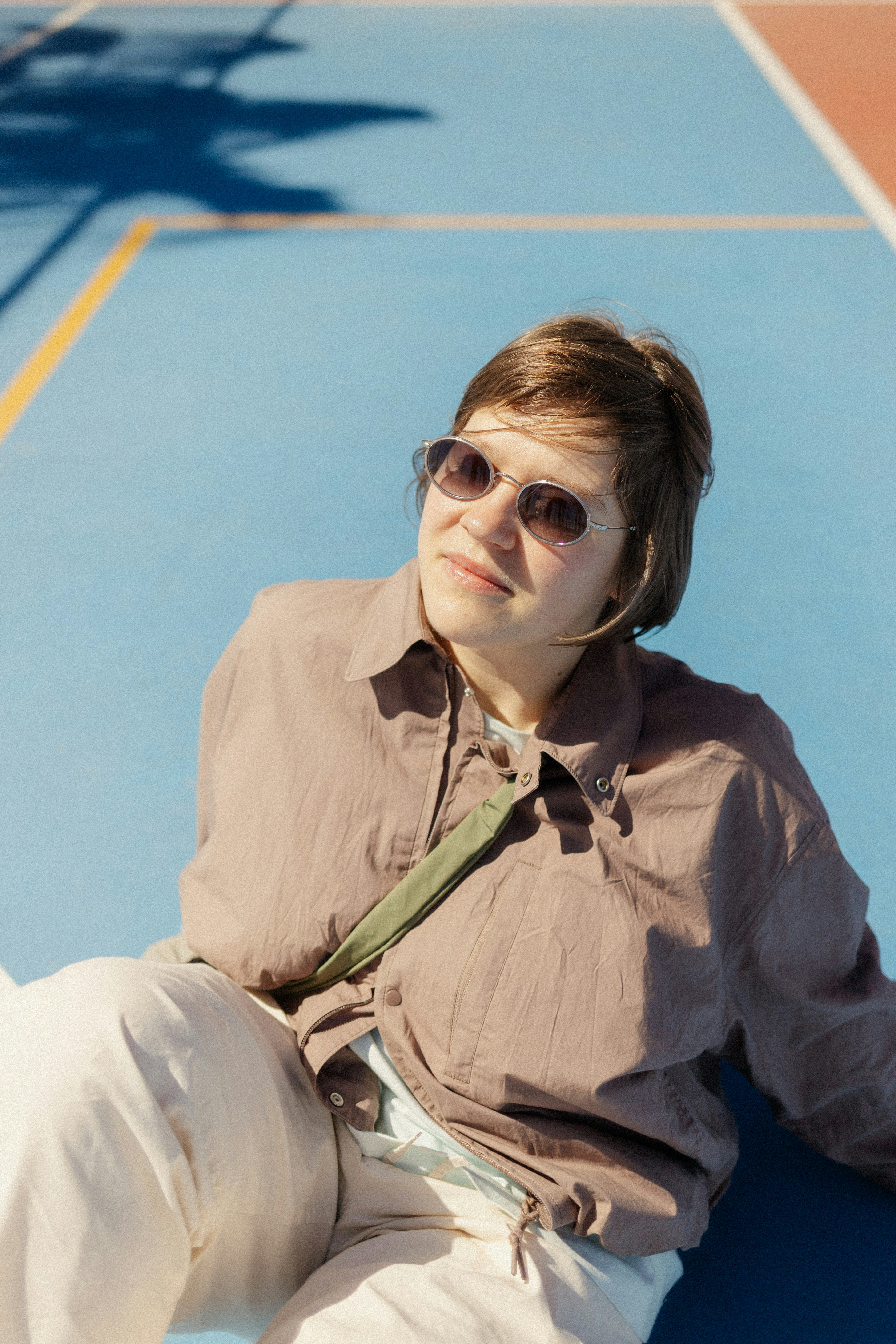 Woman in sunglasses sits outside on a sunny day.