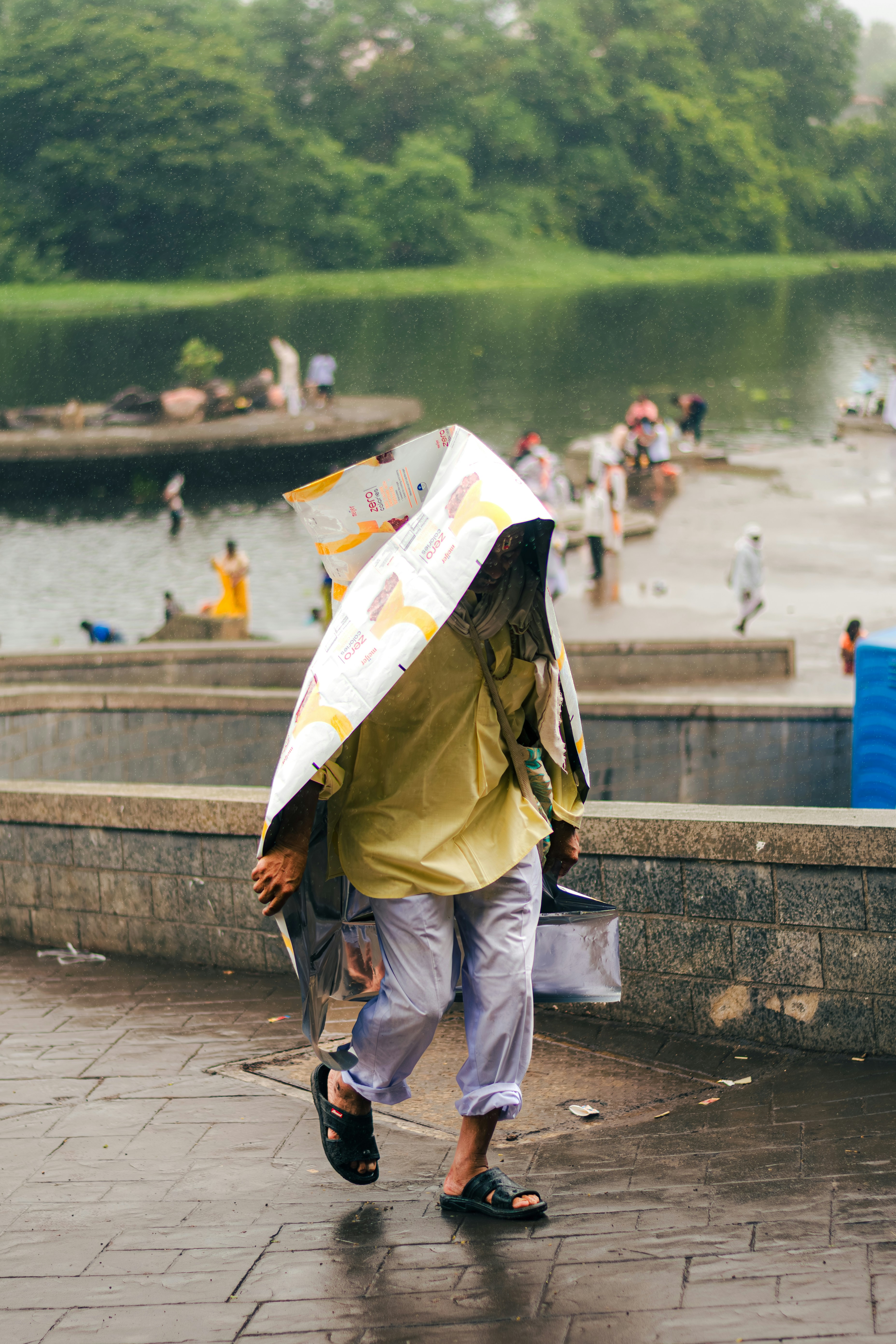 A person walks in rain, shielded by newspaper.