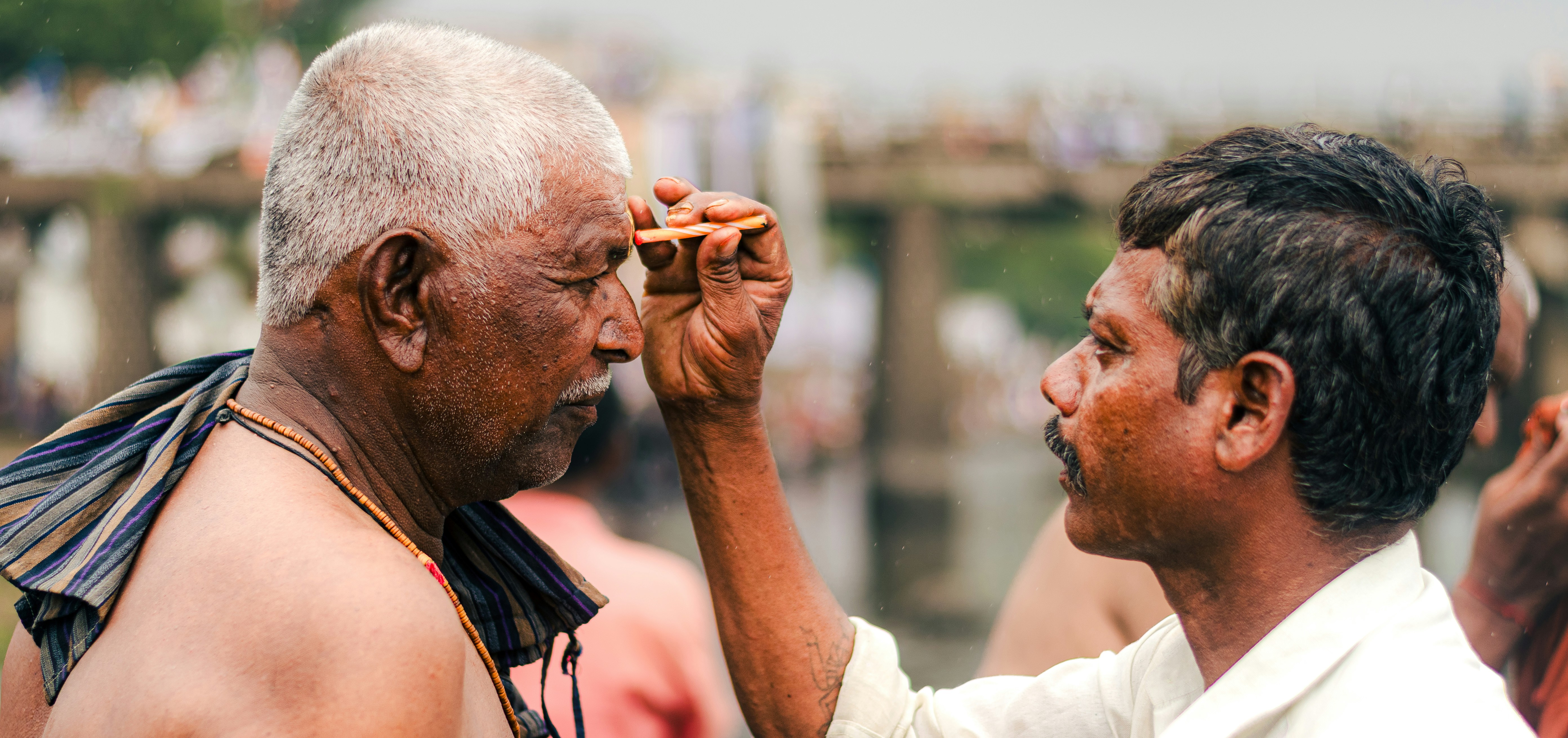 A man applies a religious mark to another.