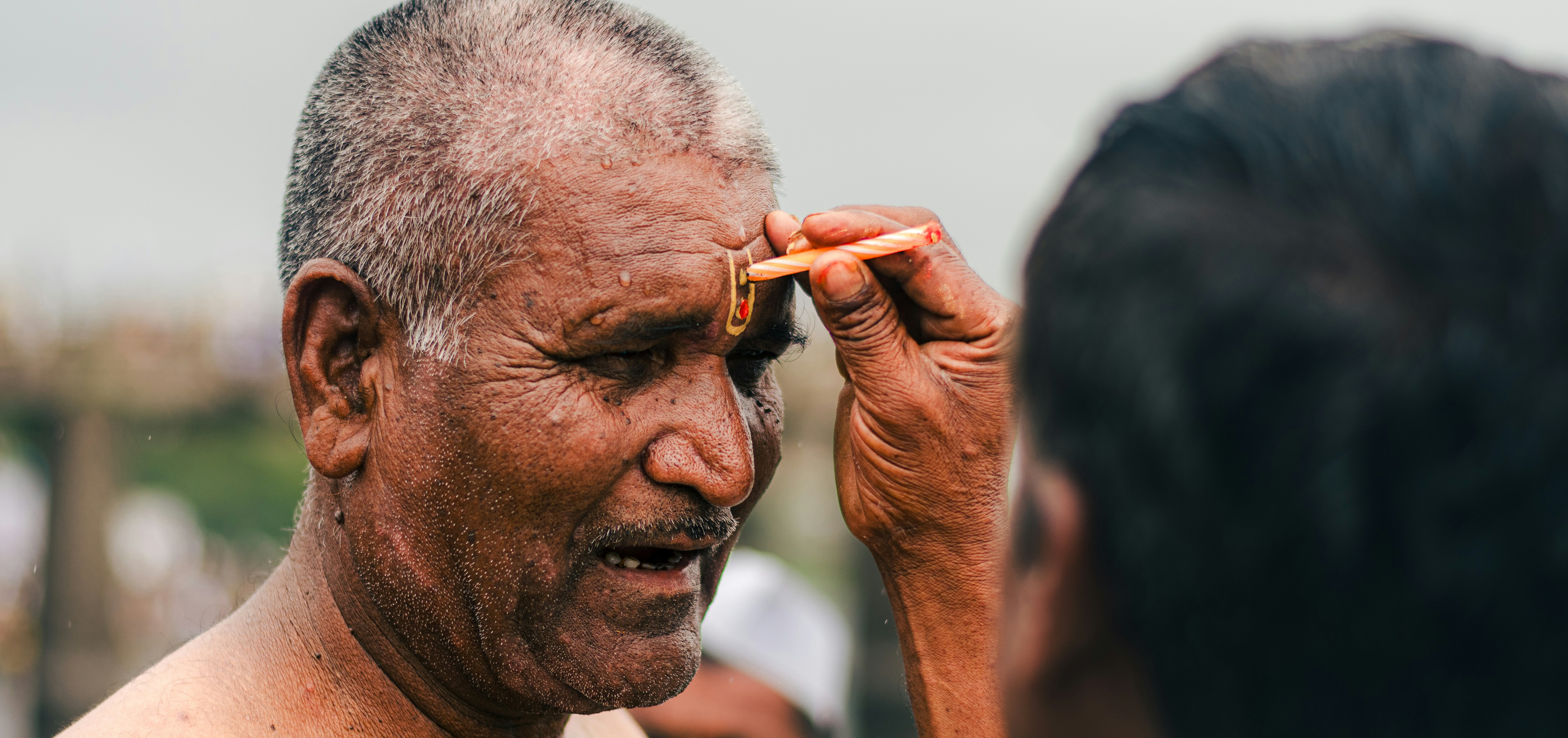 A religious ceremony takes place, the man's forehead marked.