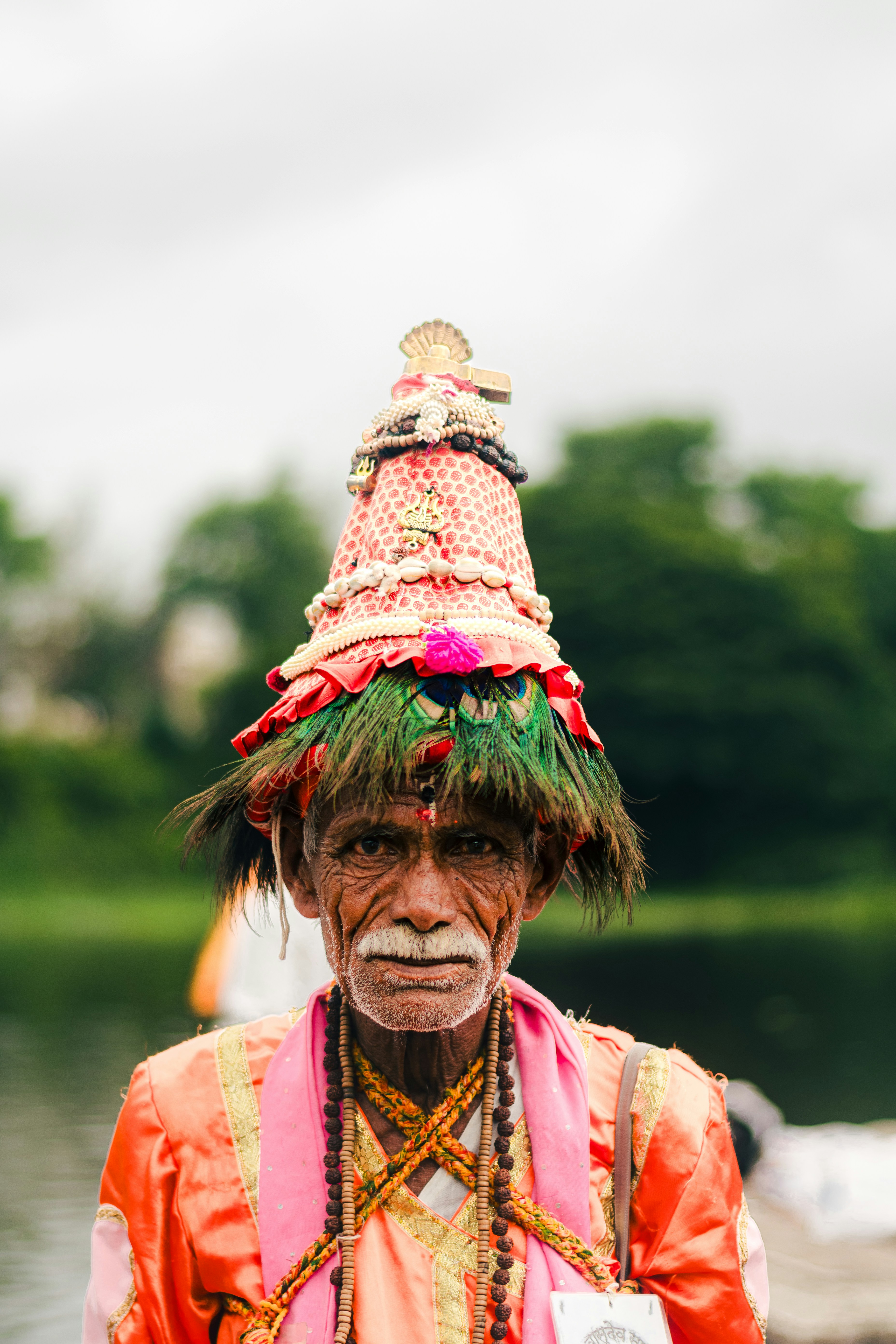 An elderly man wears a decorative hat.