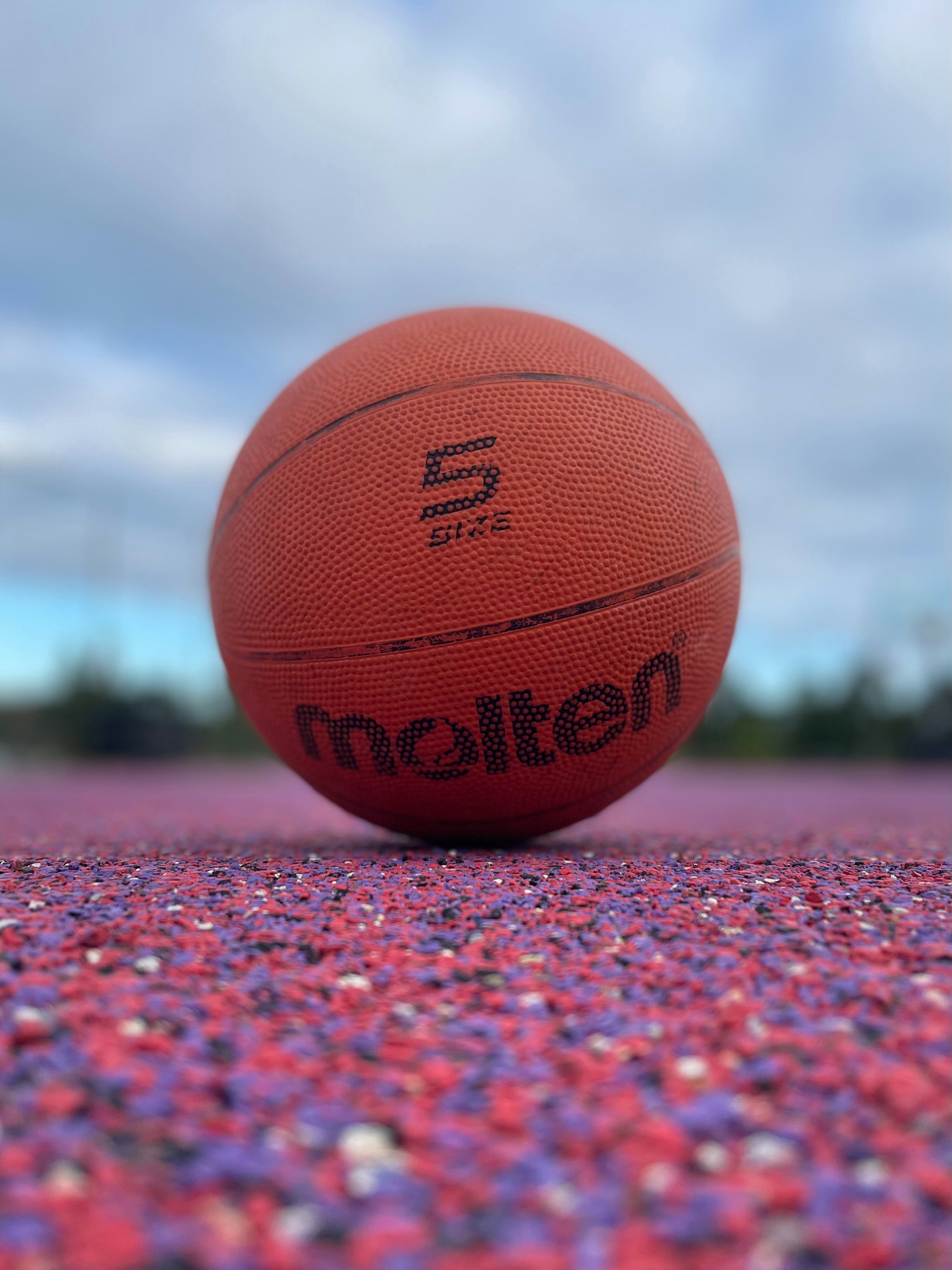 A basketball rests on a colorful court.