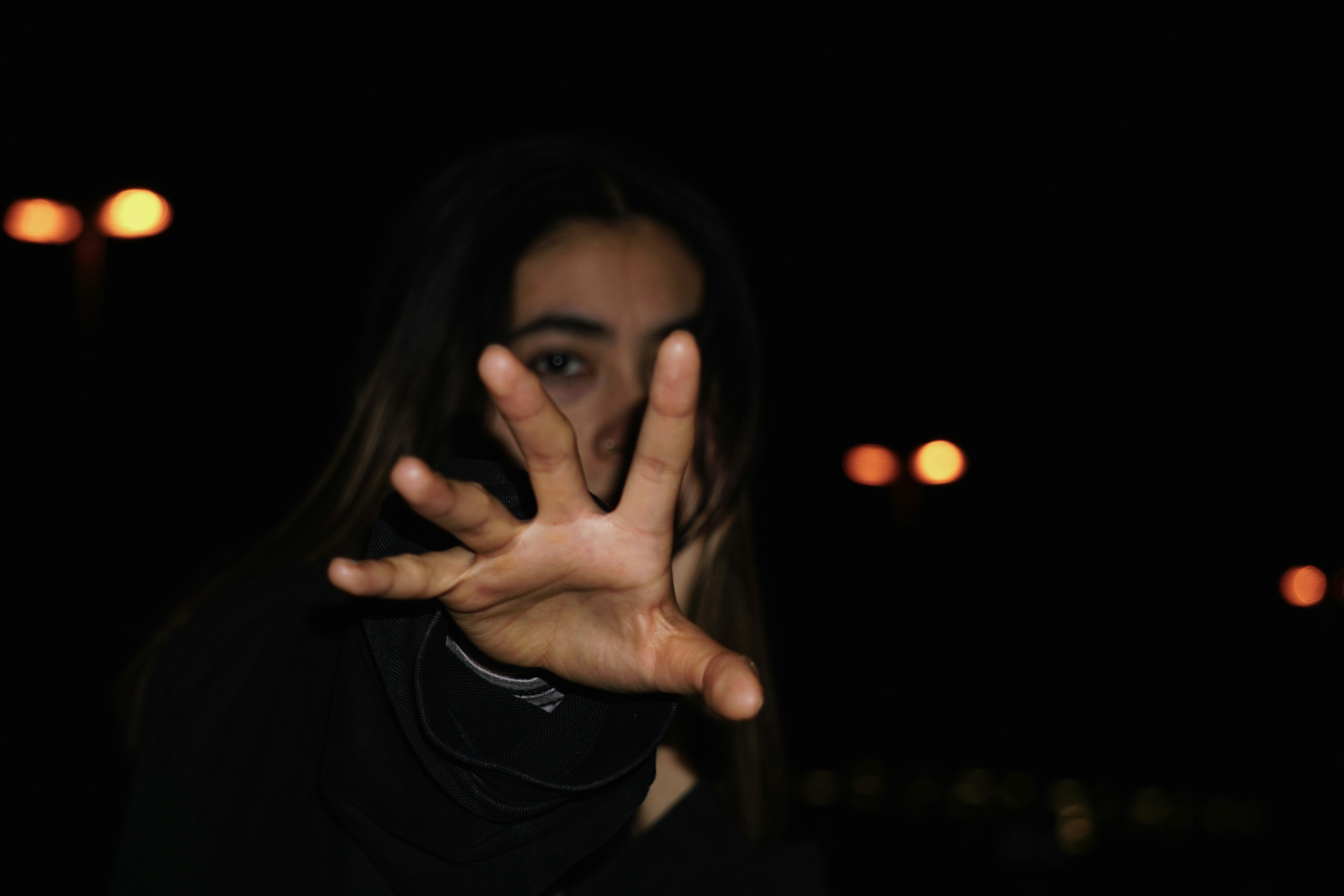 A person reaches towards the camera in darkness.
