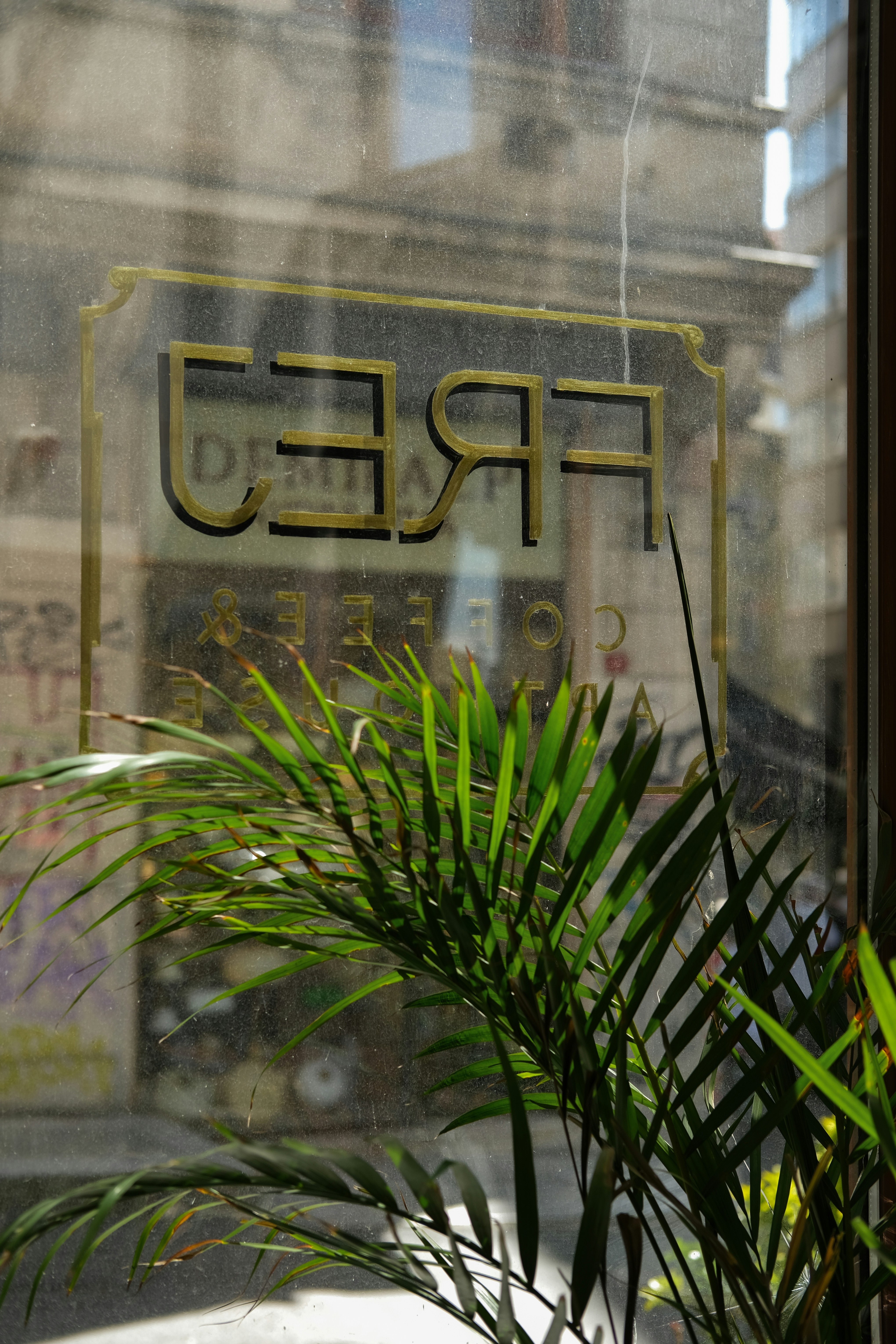 A coffee shop sign is reflected in a window.