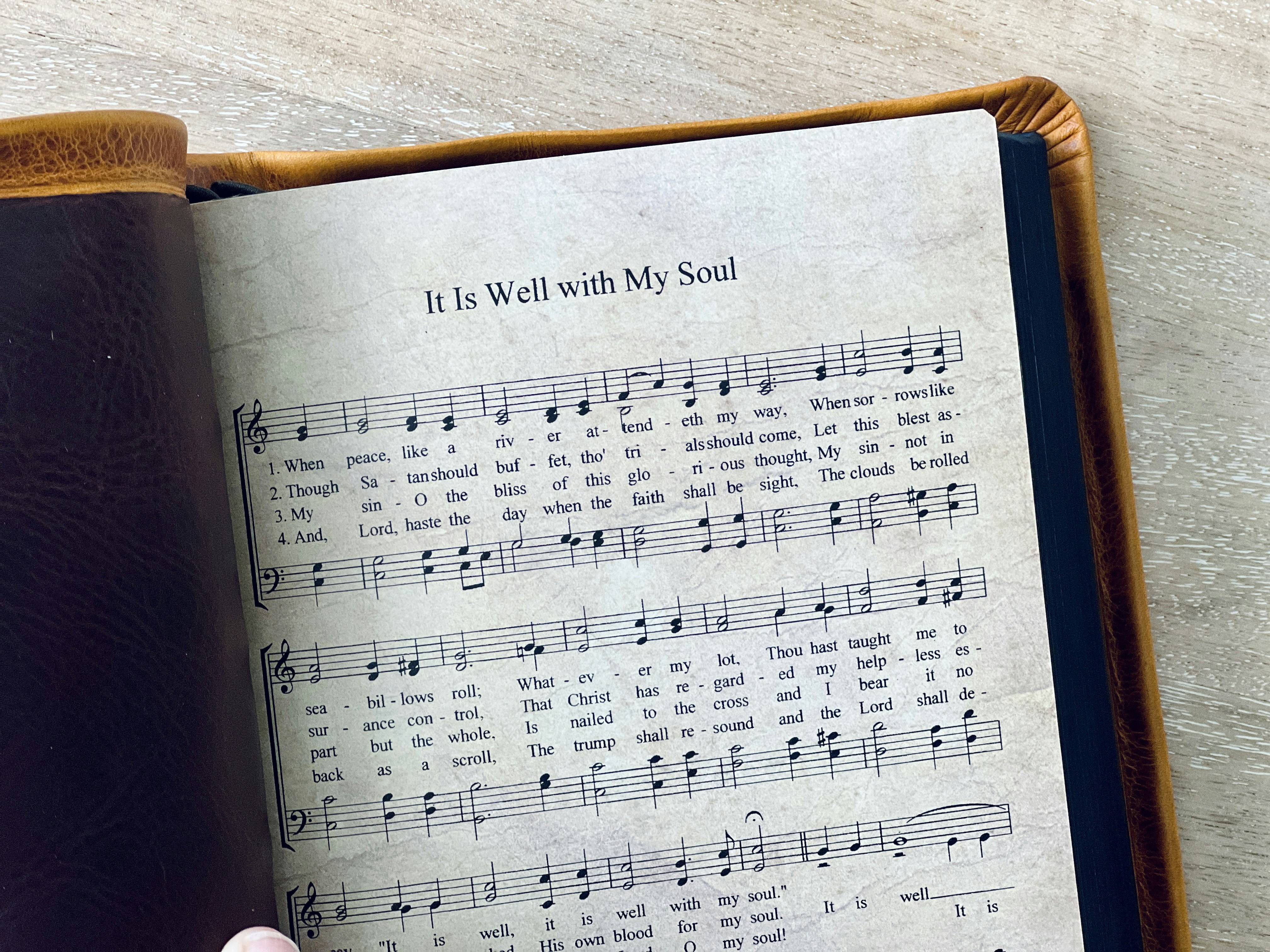 A leather-bound book displays hymn "it is well."