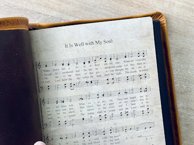 A leather-bound book displays hymn "it is well."