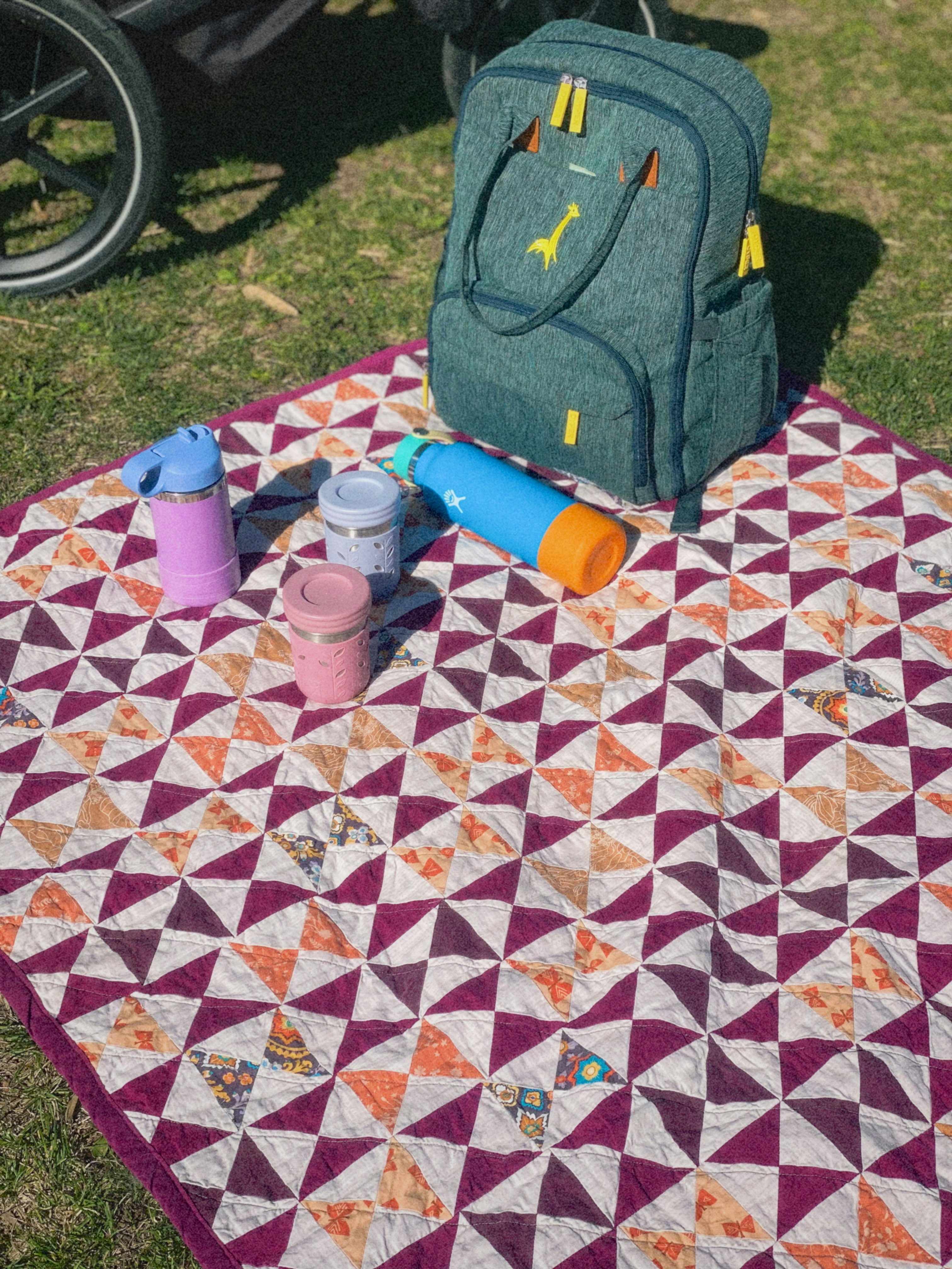 Piquenique com um cobertor colorido e uma mochila.