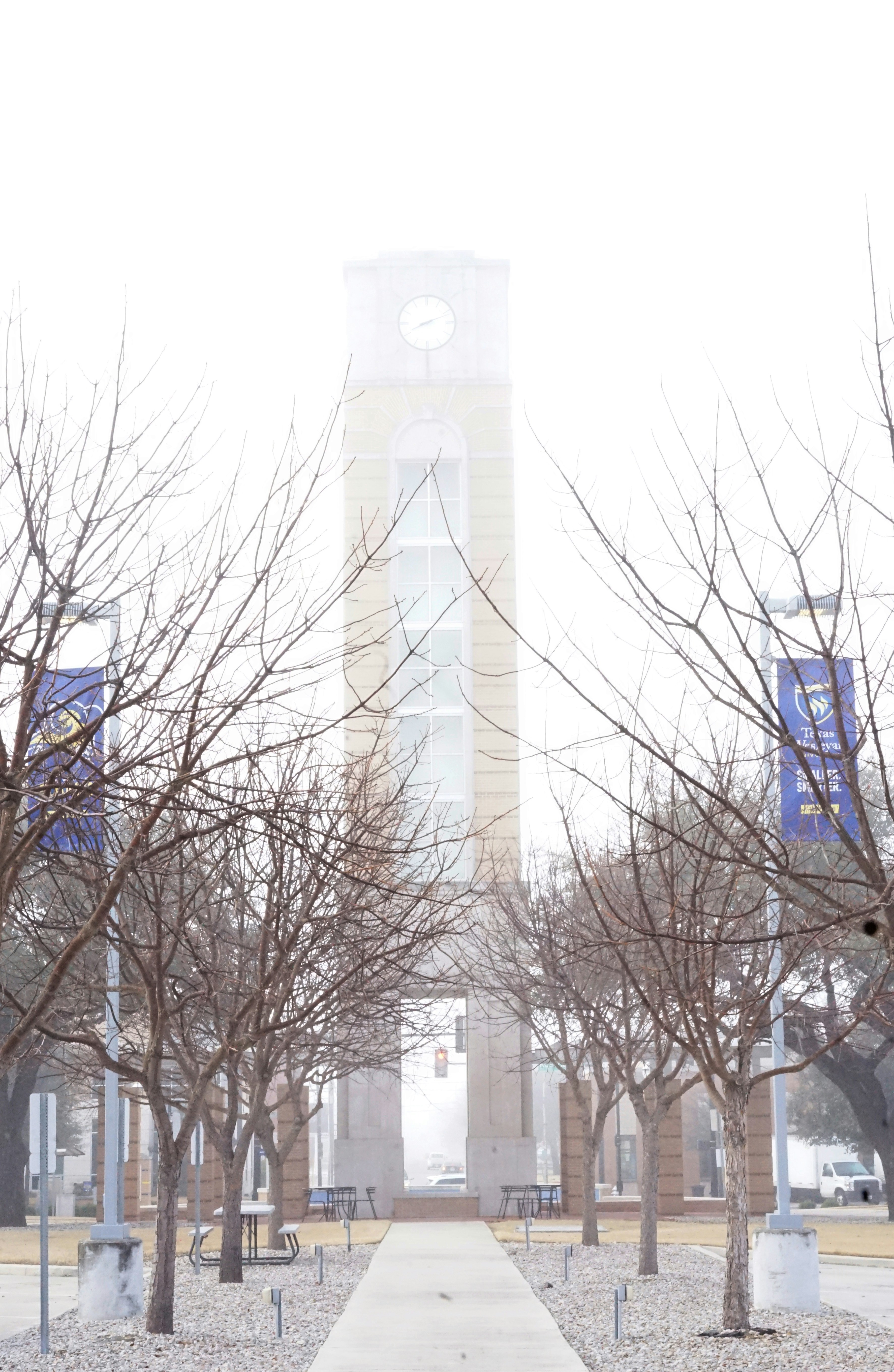 A clock tower is partially obscured by fog.