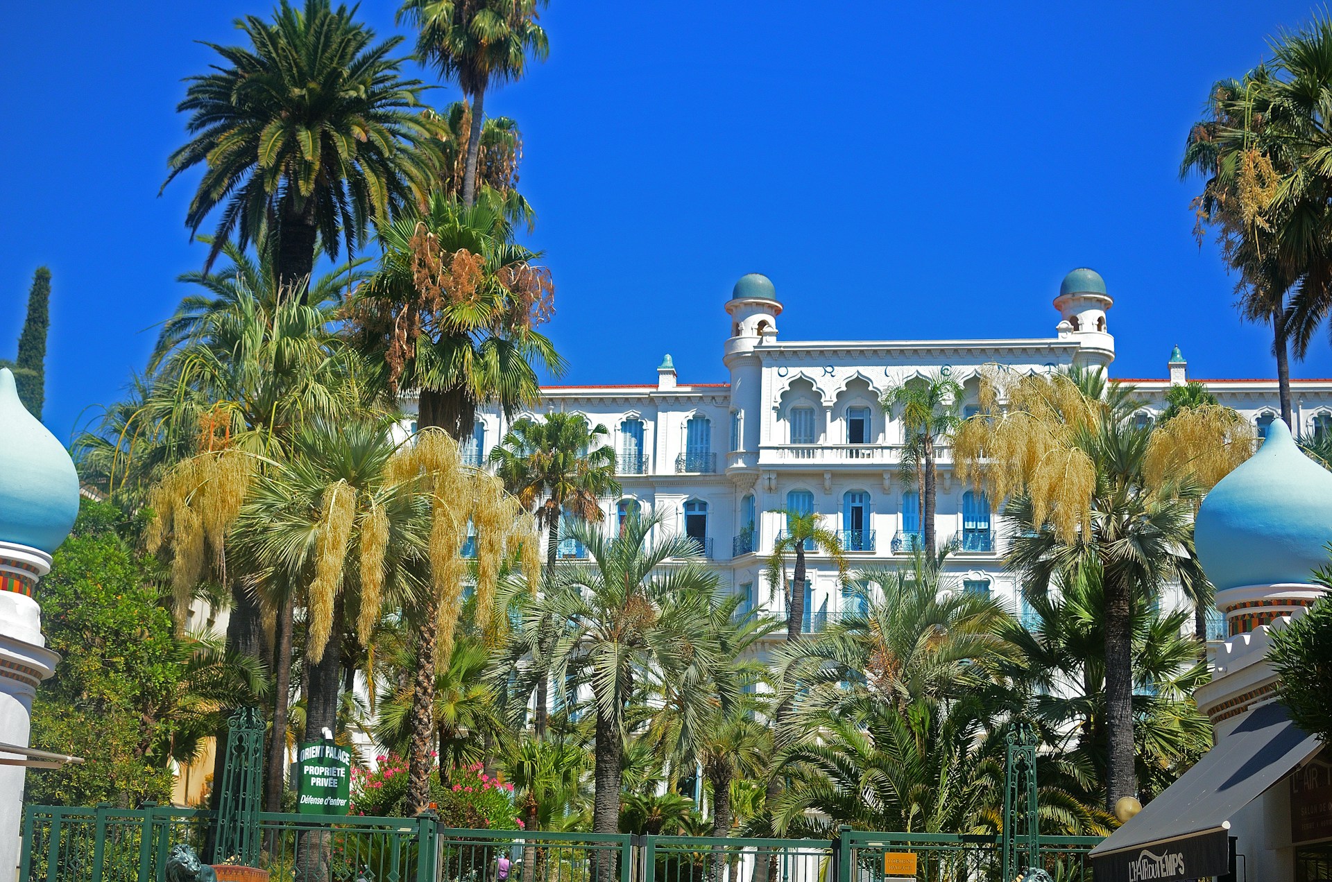 A white building stands among palm trees.