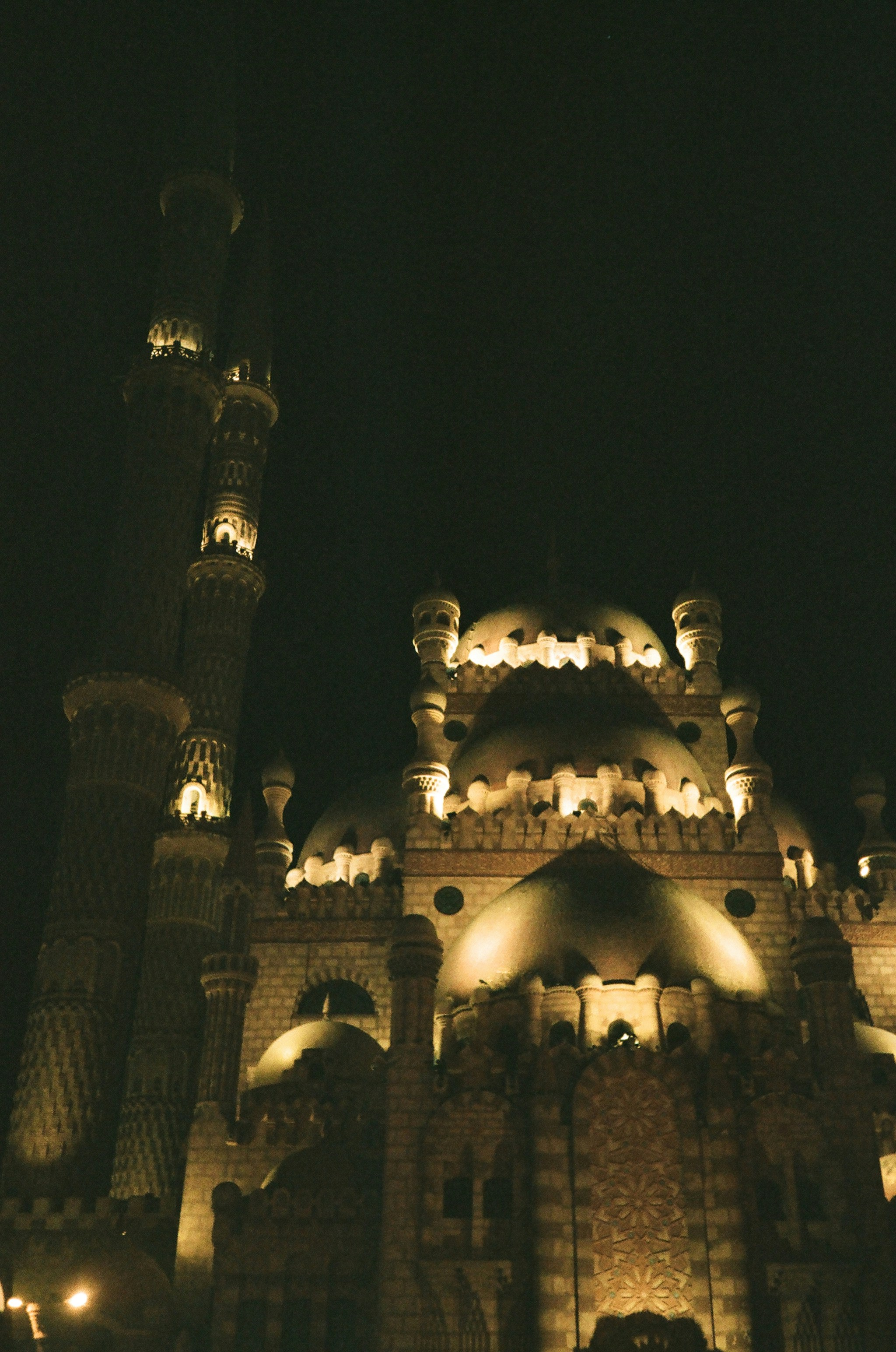 Illuminated mosque at night against the dark sky