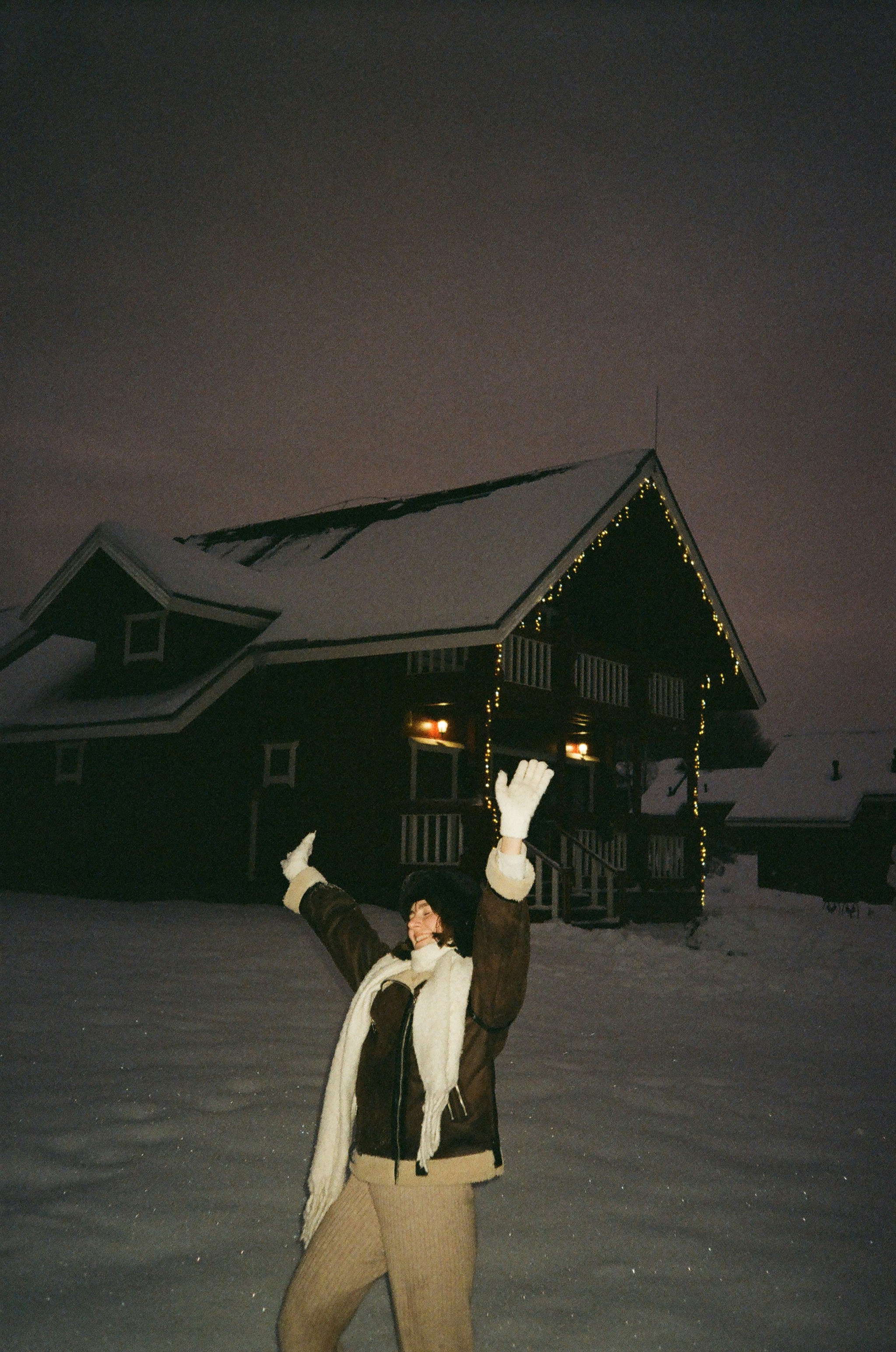 Woman celebrates in front of a snowy cabin