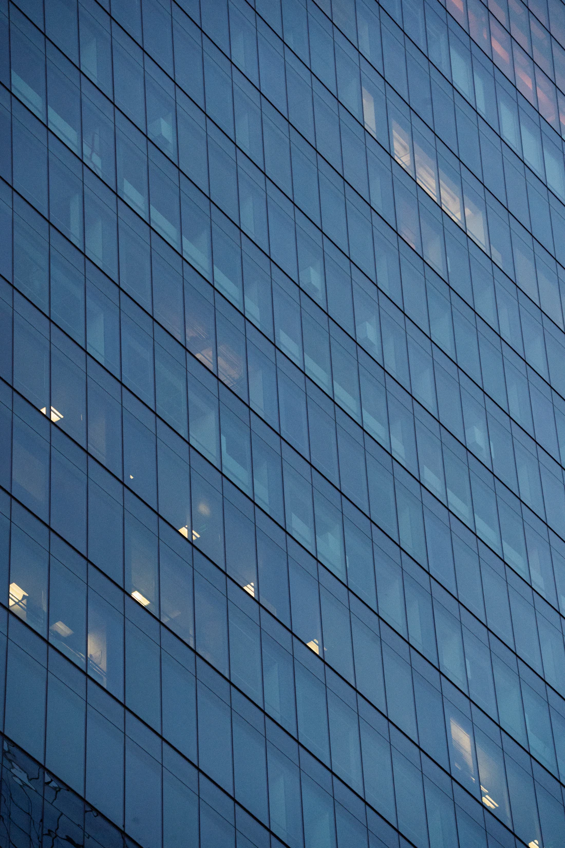 Glass facade of a modern office building lit from within at dusk
