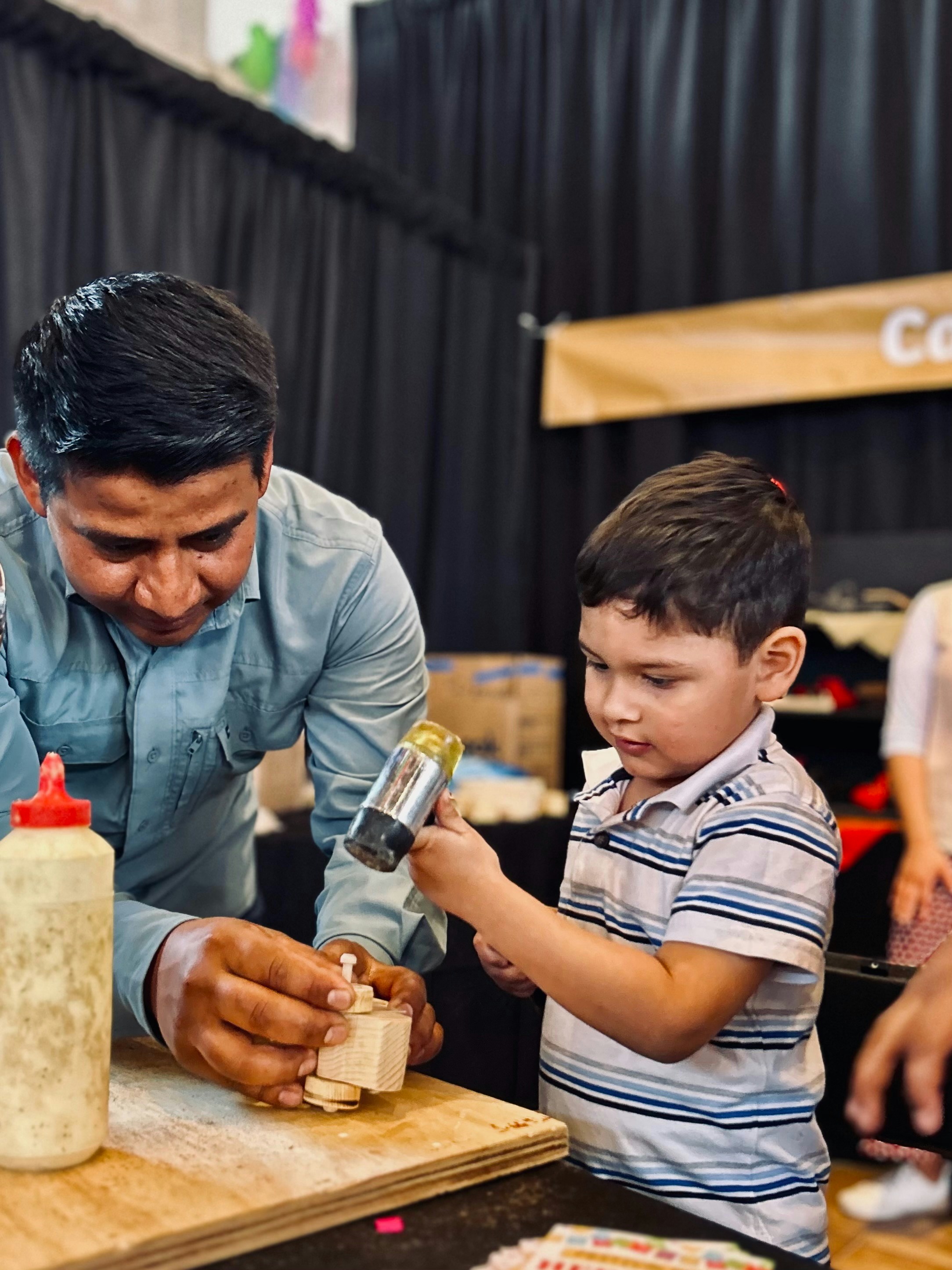 A man and child work on a wooden project.