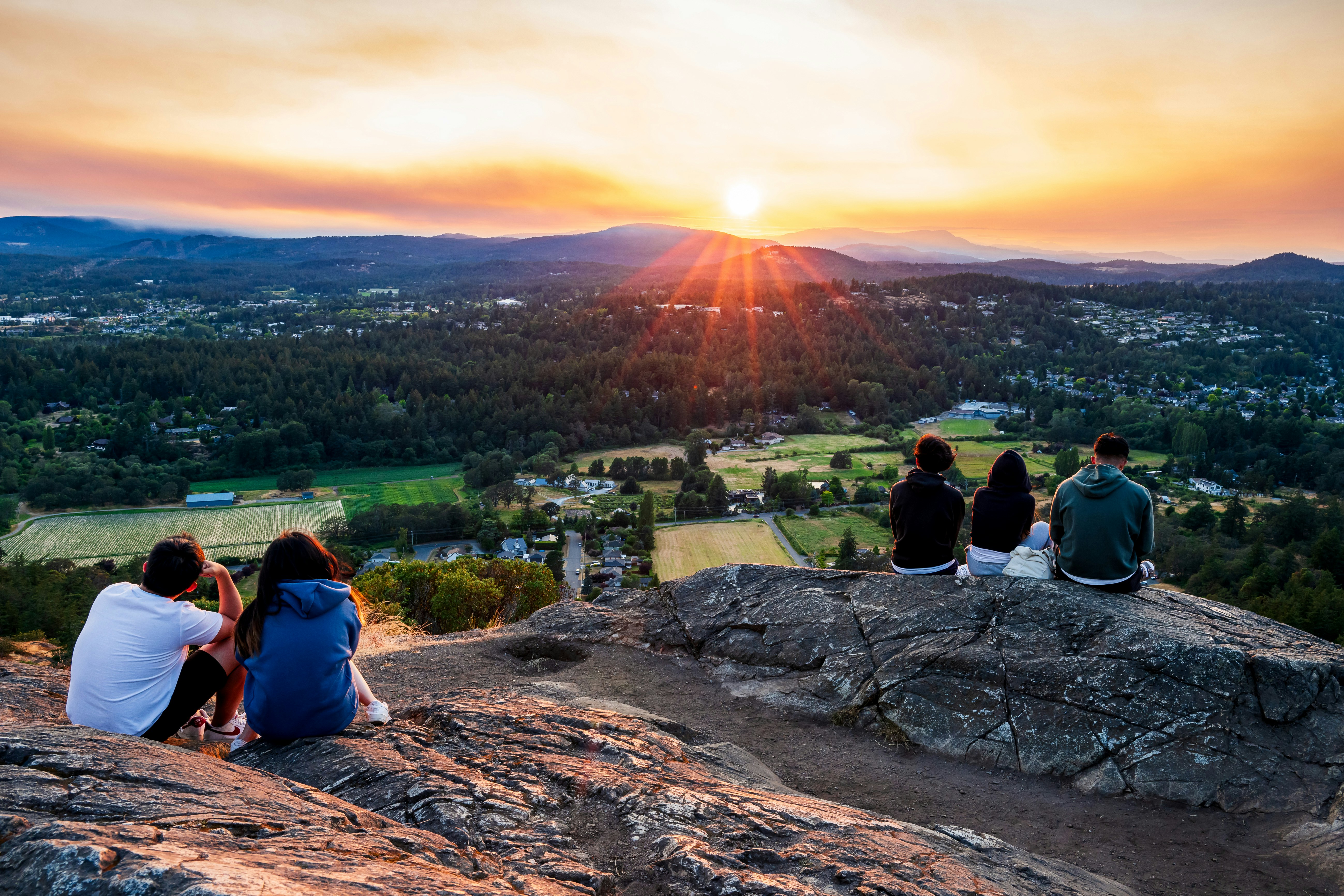 Friends watch a gorgeous sunset over the scenic landscape.