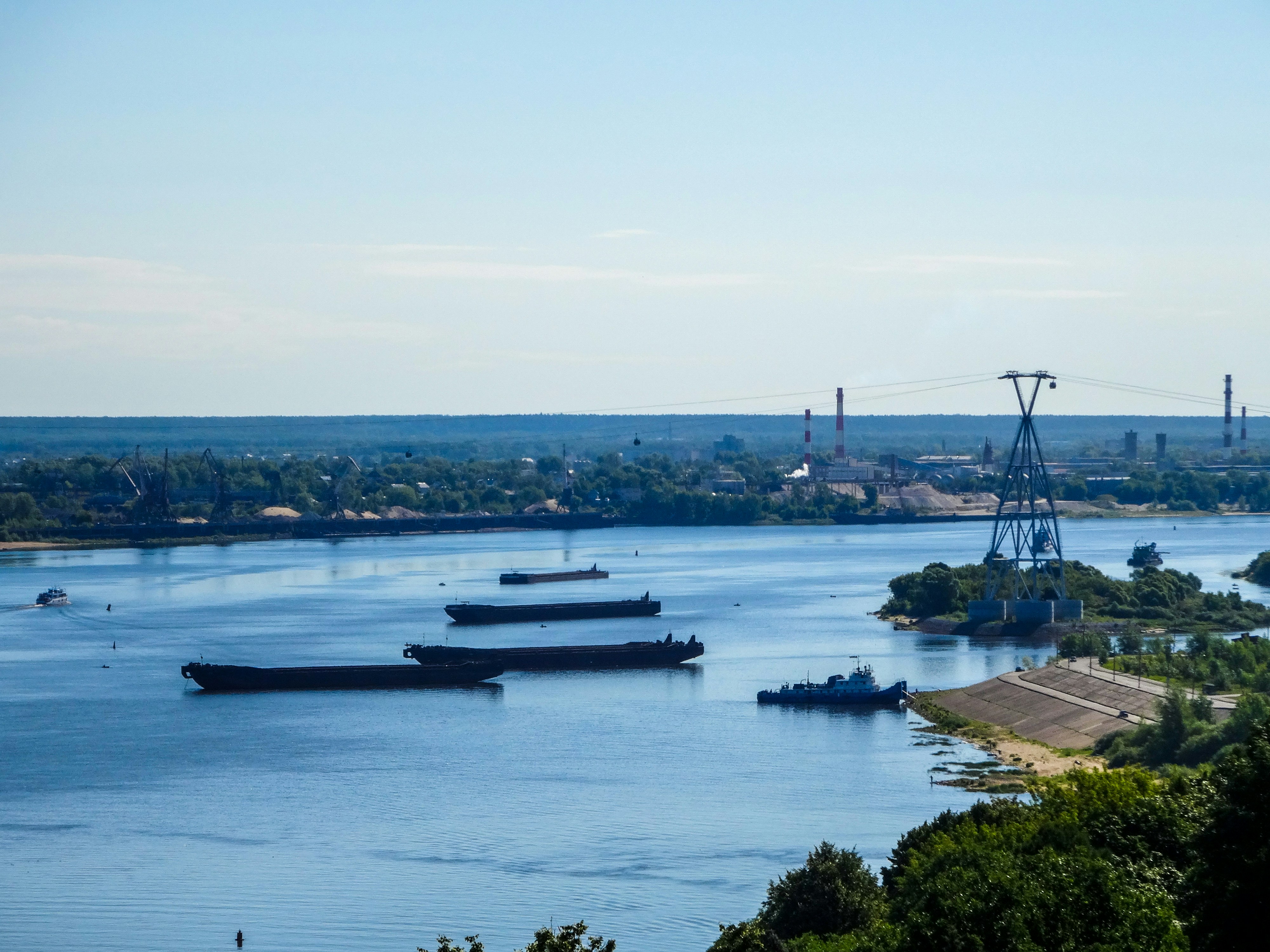 Cargo ships sail on a wide, blue river.