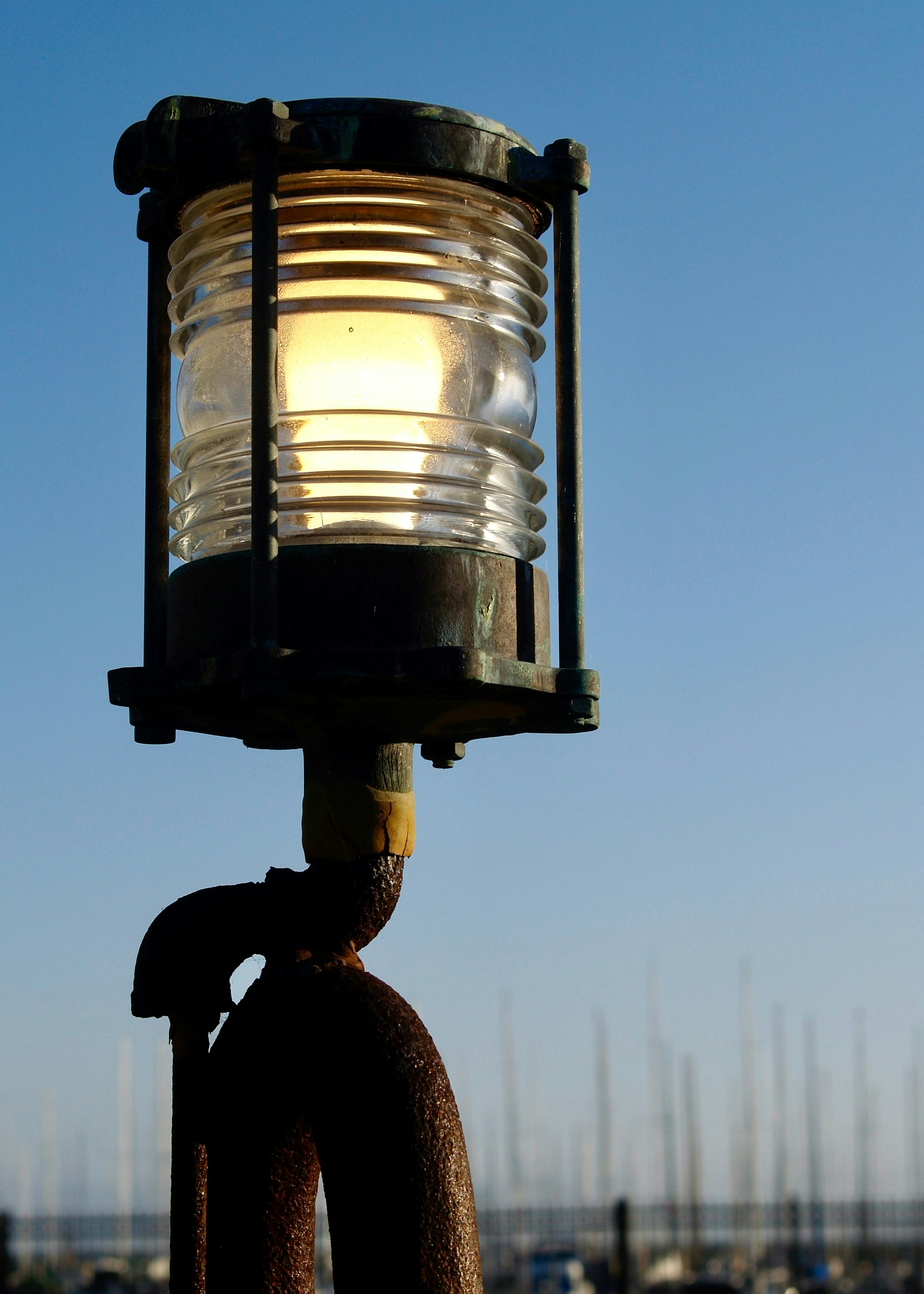 A lit nautical lamp against a clear sky.