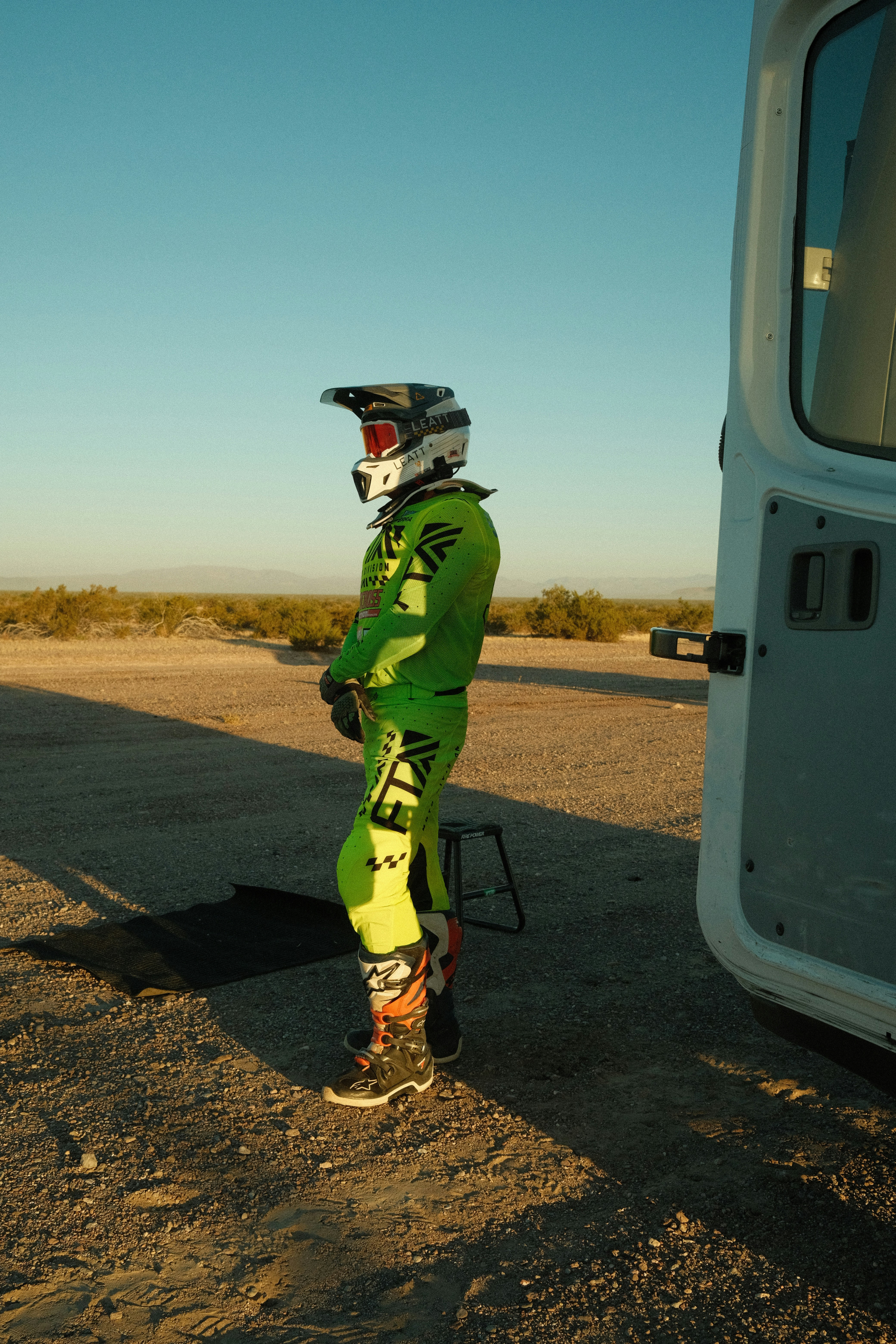 A motocross rider stands ready outdoors.
