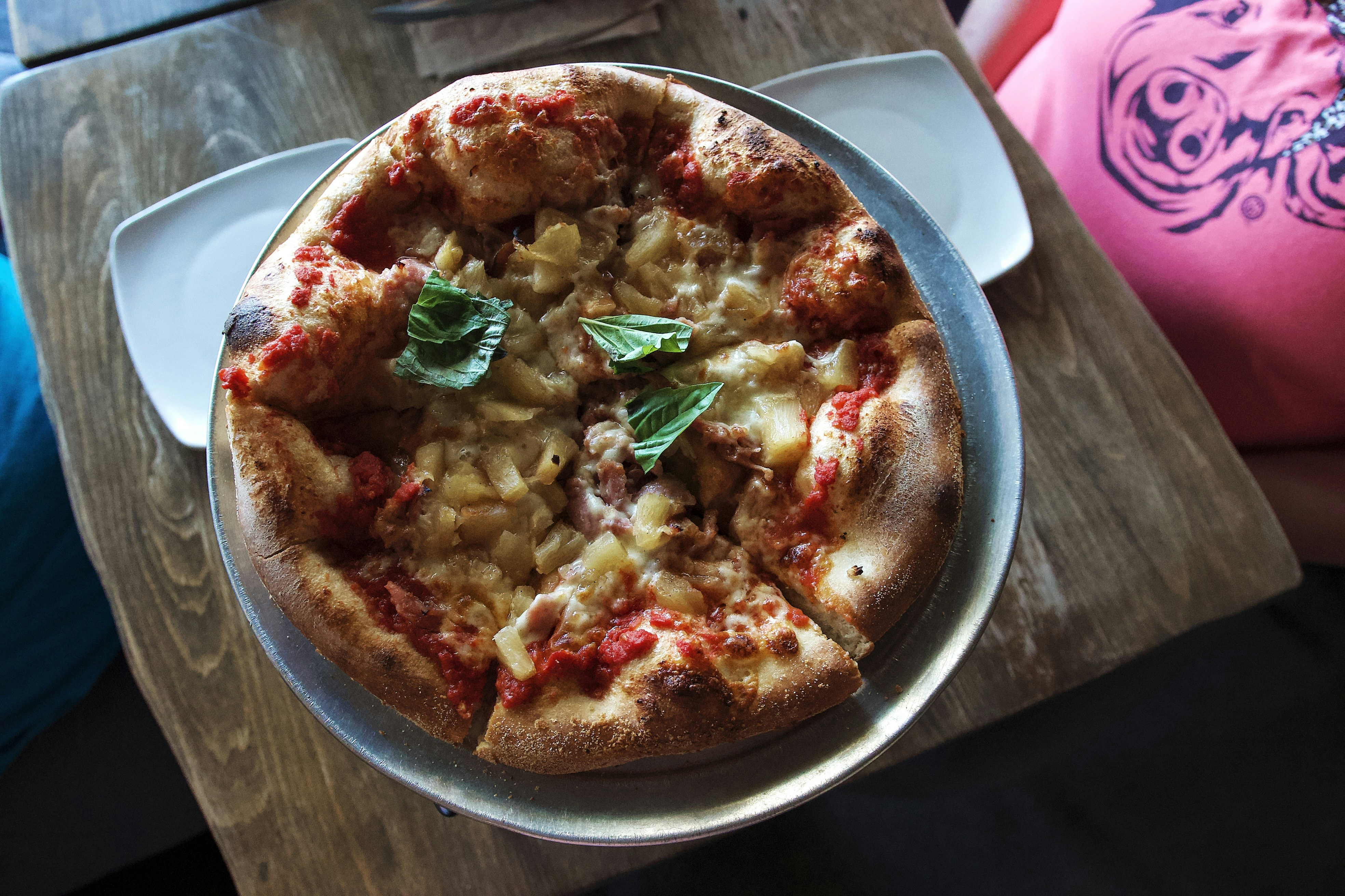 Delicious pizza with fresh basil is served on a plate.