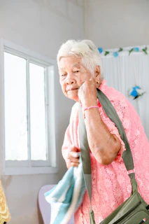 An elderly woman holds her bag, ready to leave