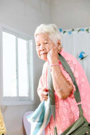 An elderly woman holds her bag, ready to leave