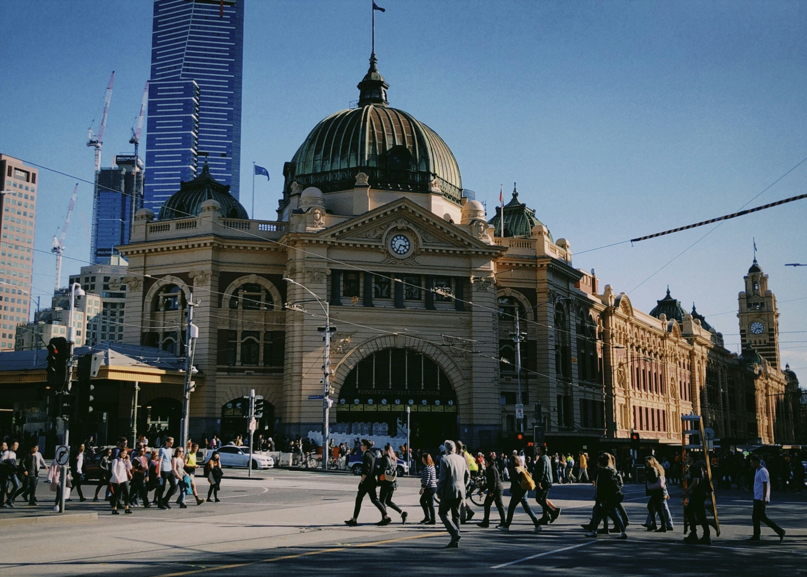 People cross the street in front of a building.