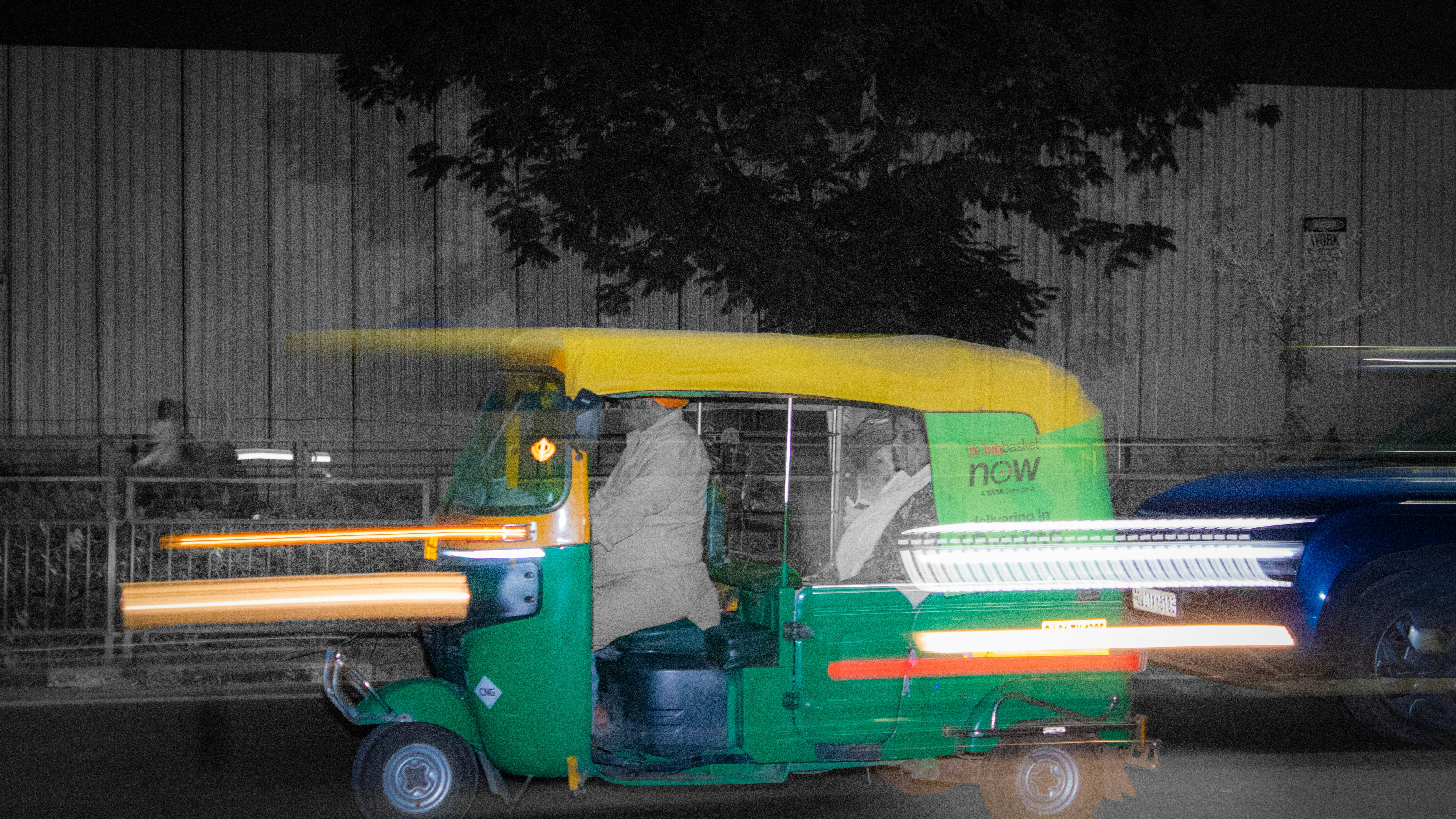 A blurred auto rickshaw drives at night.