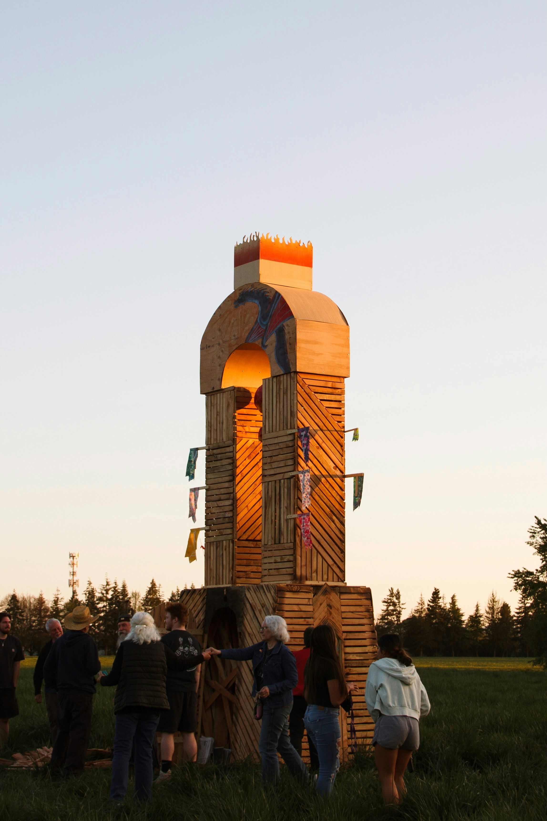 People gather near a large wooden structure.