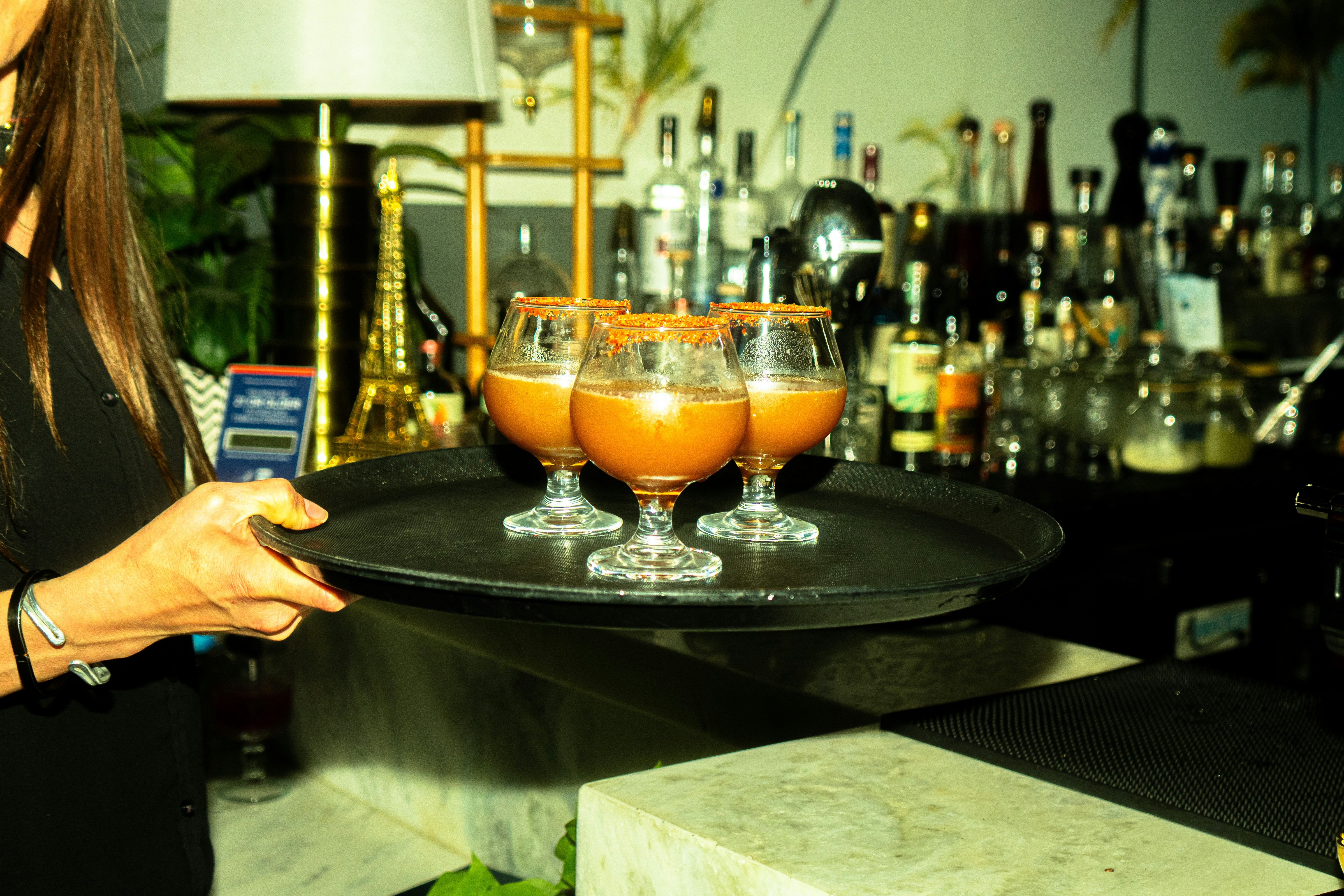 A waitress carries cocktails on a serving tray.