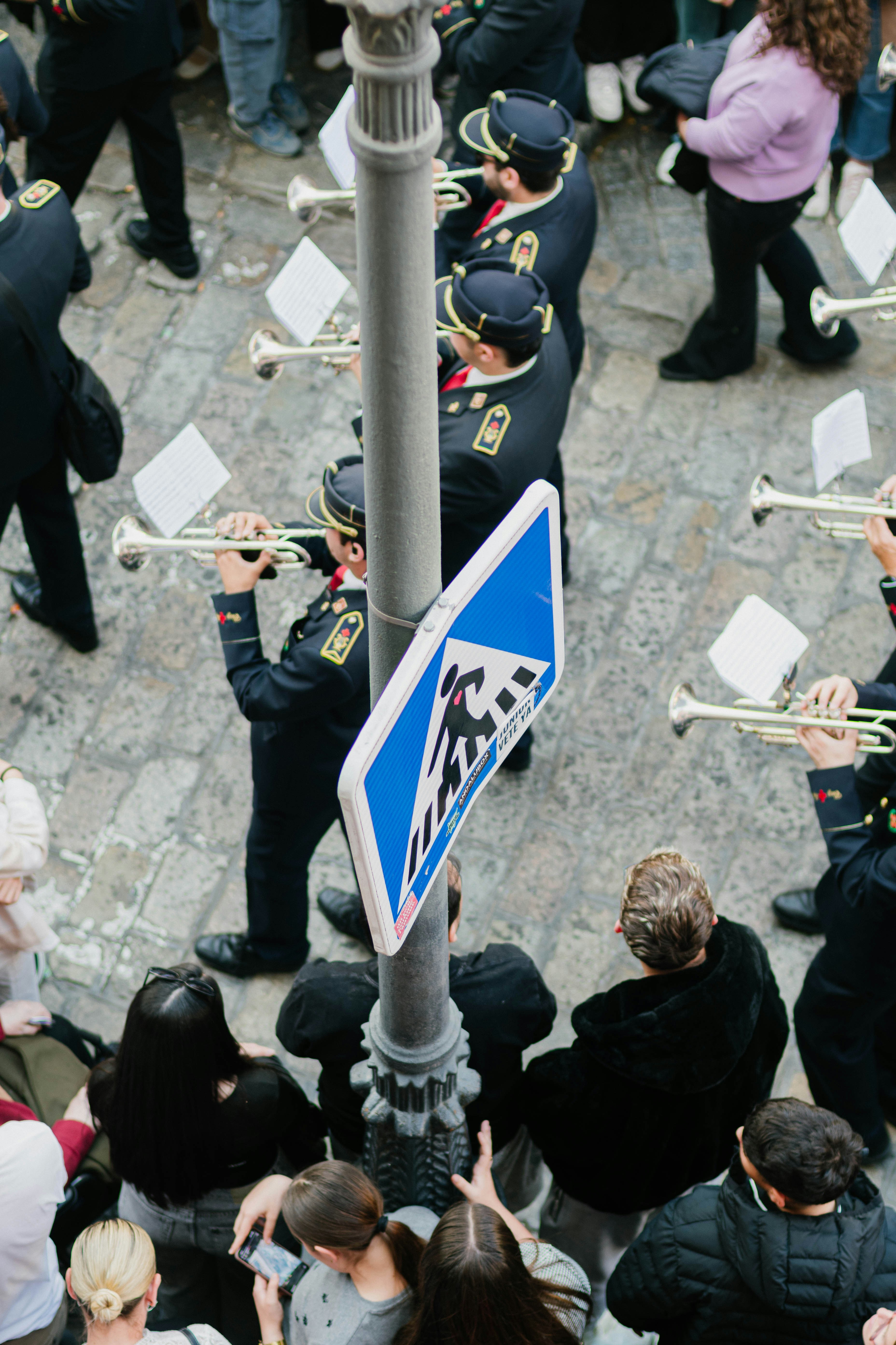 A marching band plays in a crowded street.