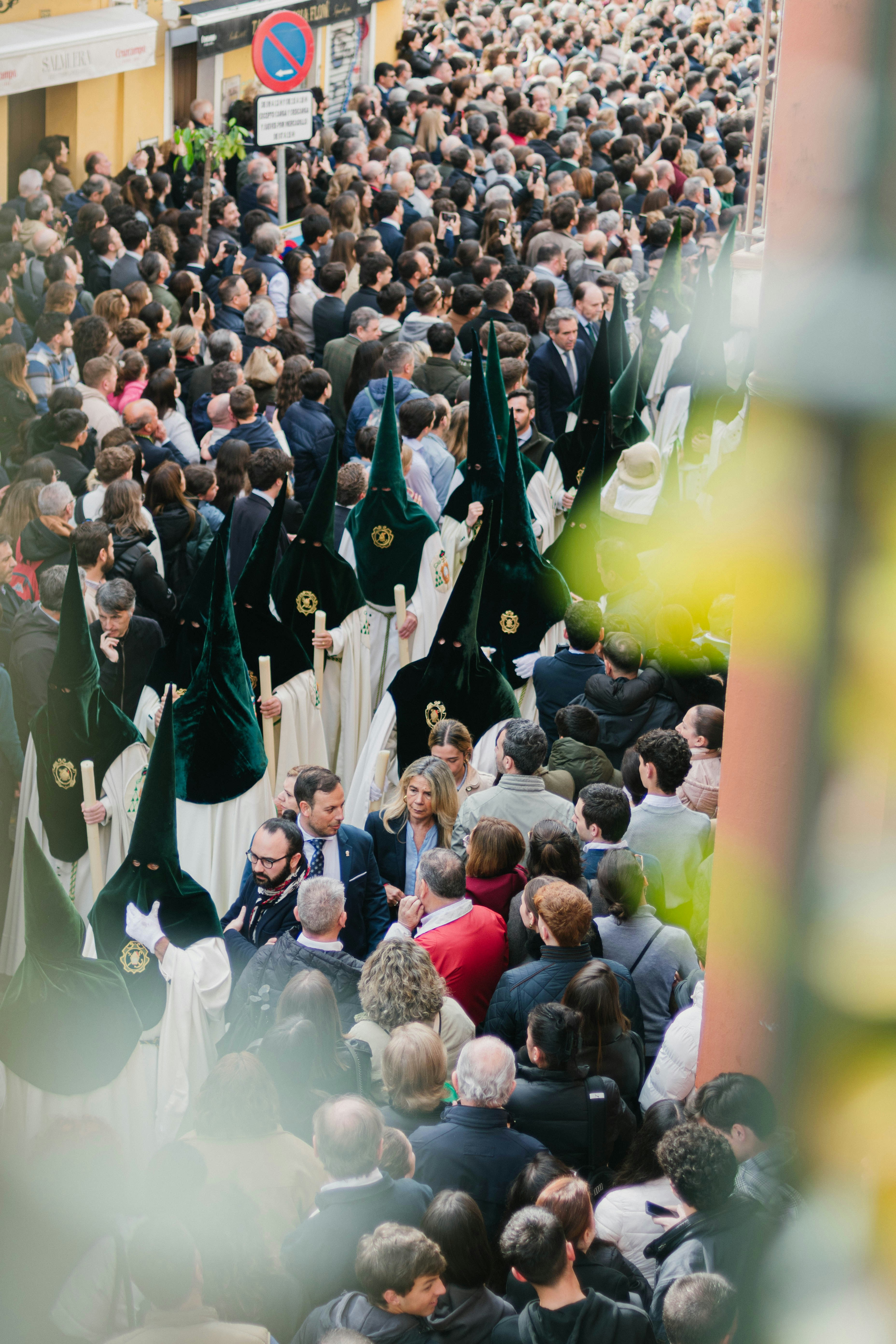 A religious procession with hooded figures moves through a crowd.