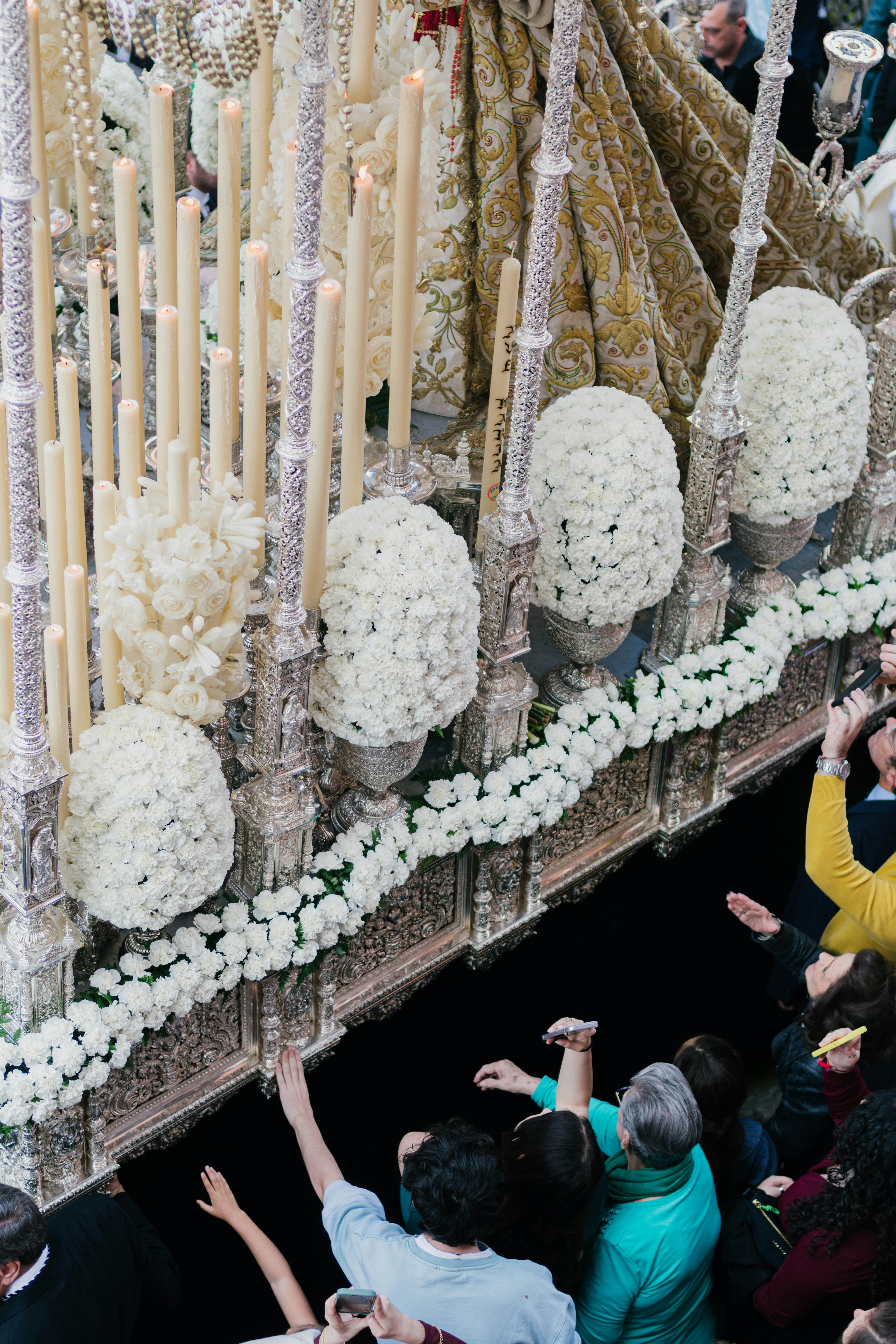People reach for a decorated religious procession.