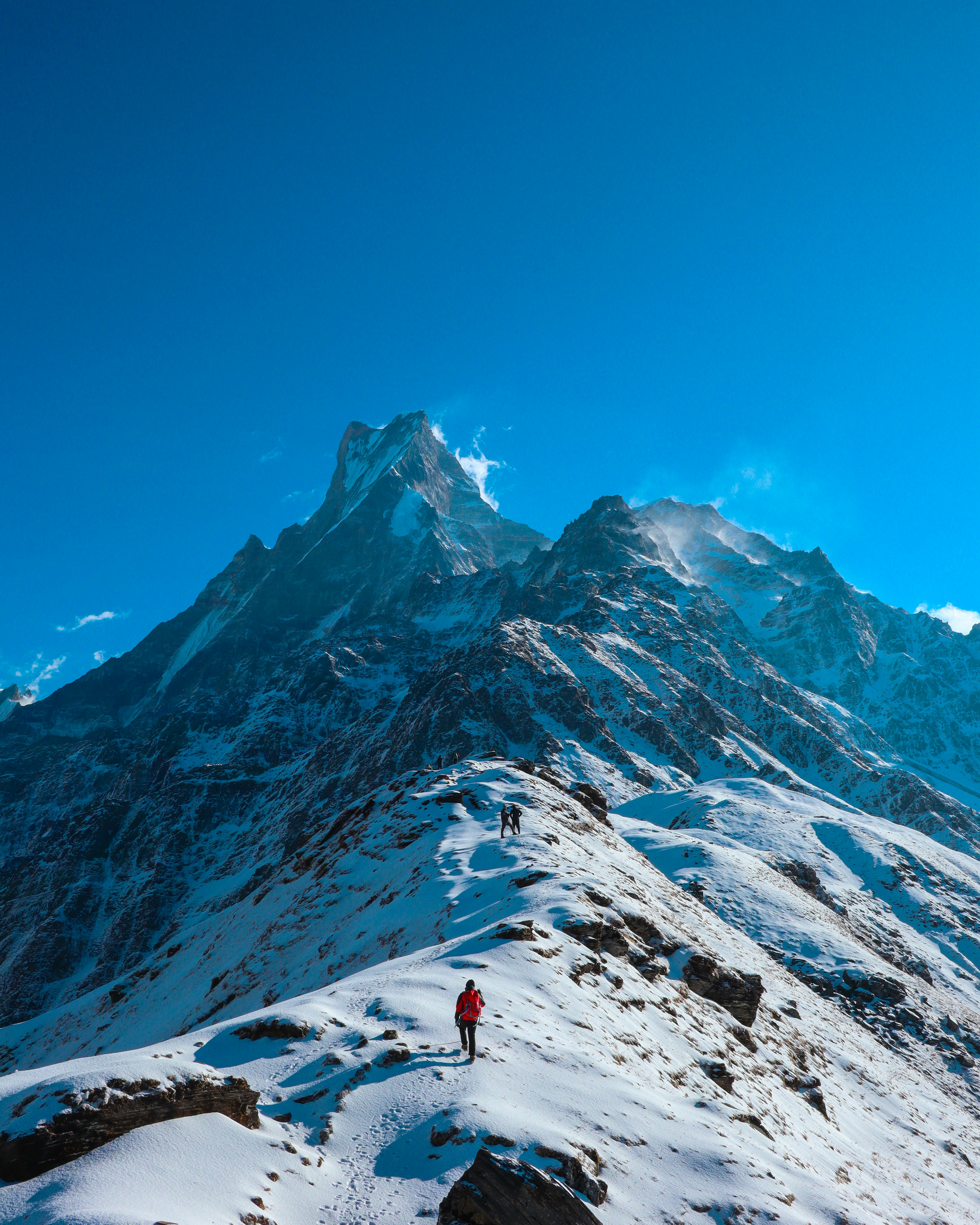 Hikers trek across a snowy mountain ridge.