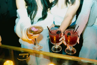 Friends hold cocktails, enjoying a night out.