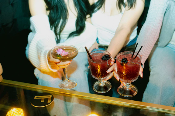 Friends hold cocktails, enjoying a night out.