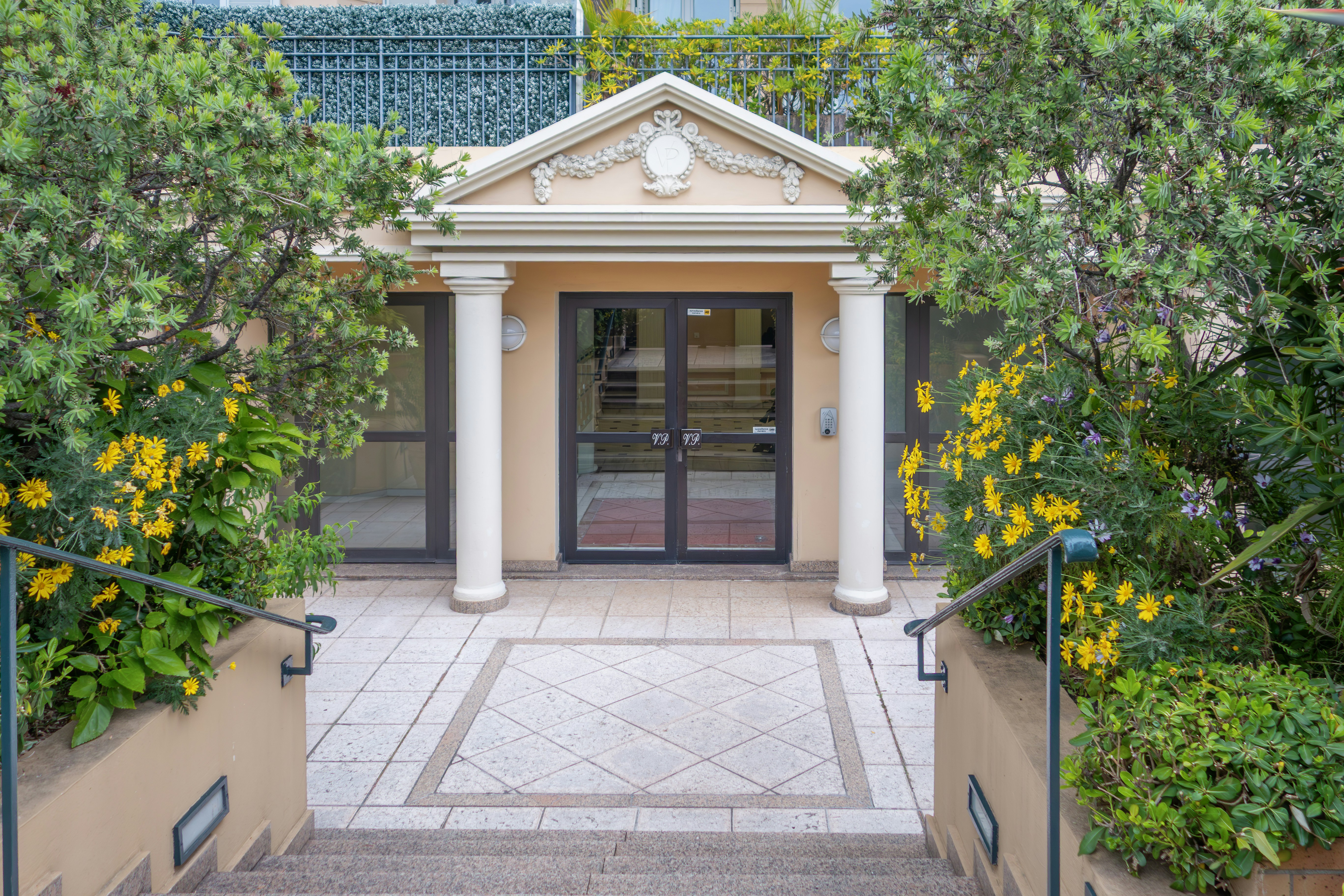 Autumn view of a suburban long-term care home entrance with sunflower planters and fall foliage.